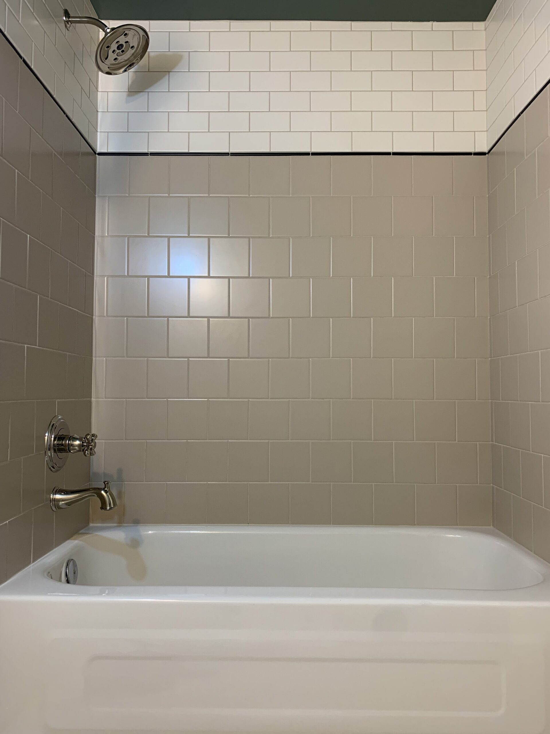 subway tile applied in a pattern in a shower with beige, black and white tiles of different shapes, tiled over old tile