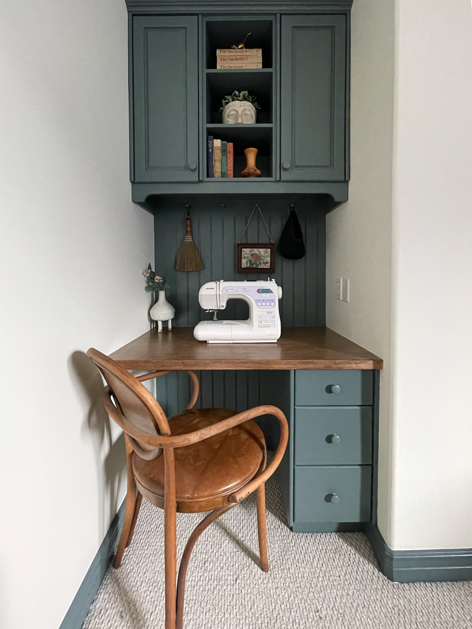 teal painted desk with wood desk top, upper cabinets with shelves, vintage chair, sewing maching on desk