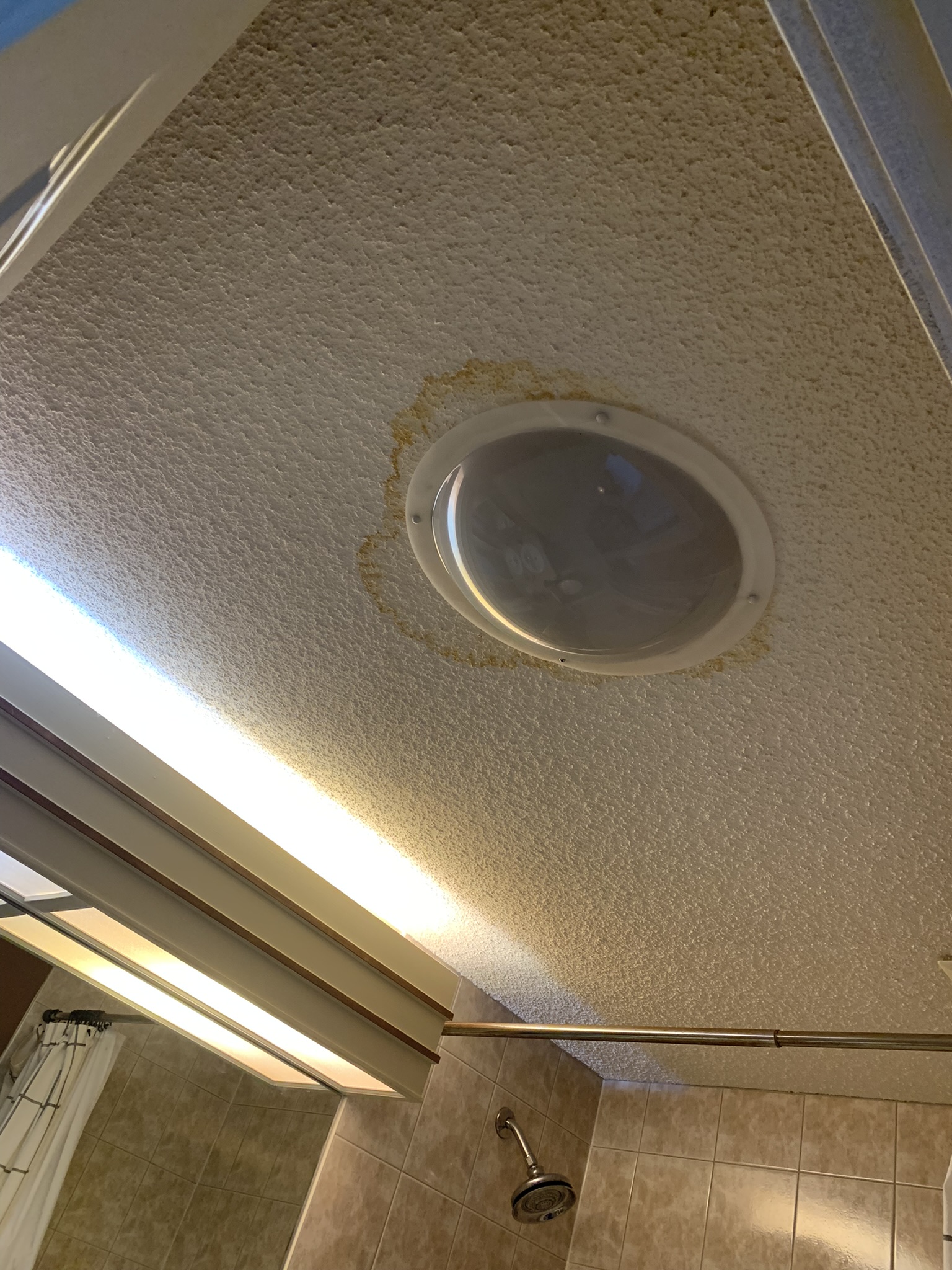 Popcorn ceiling stained with water damage around a sun tunnel skylight