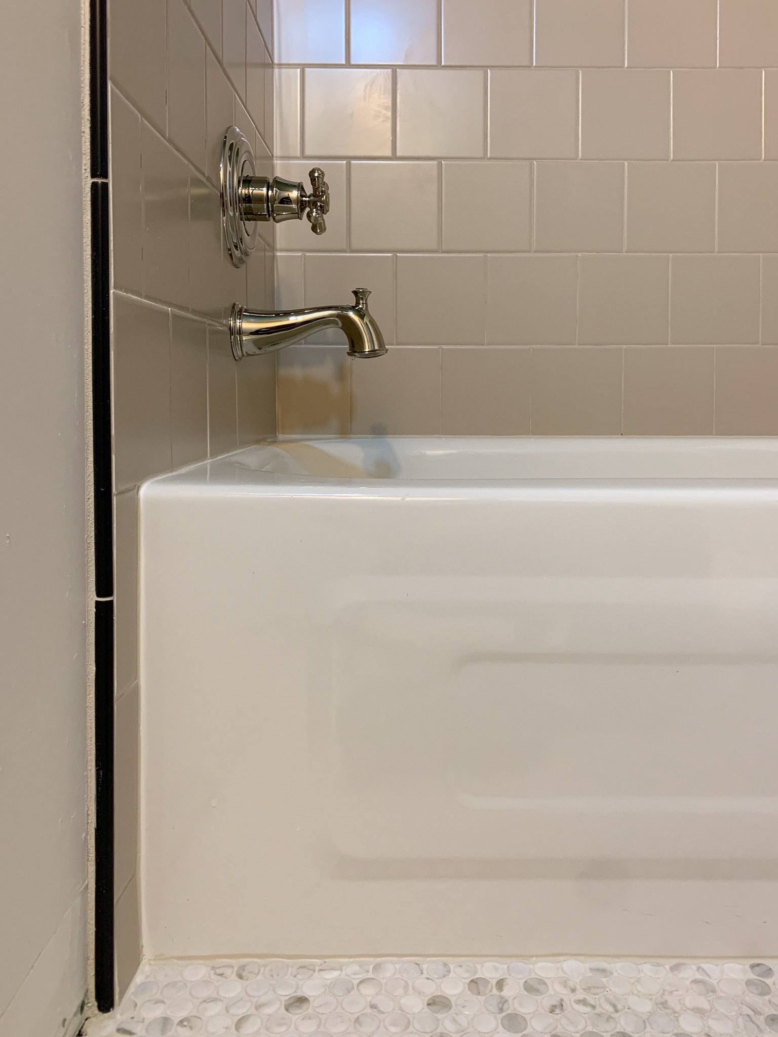 beige 6x6 shower with polished nickel fixtures and a black pencil tile edge