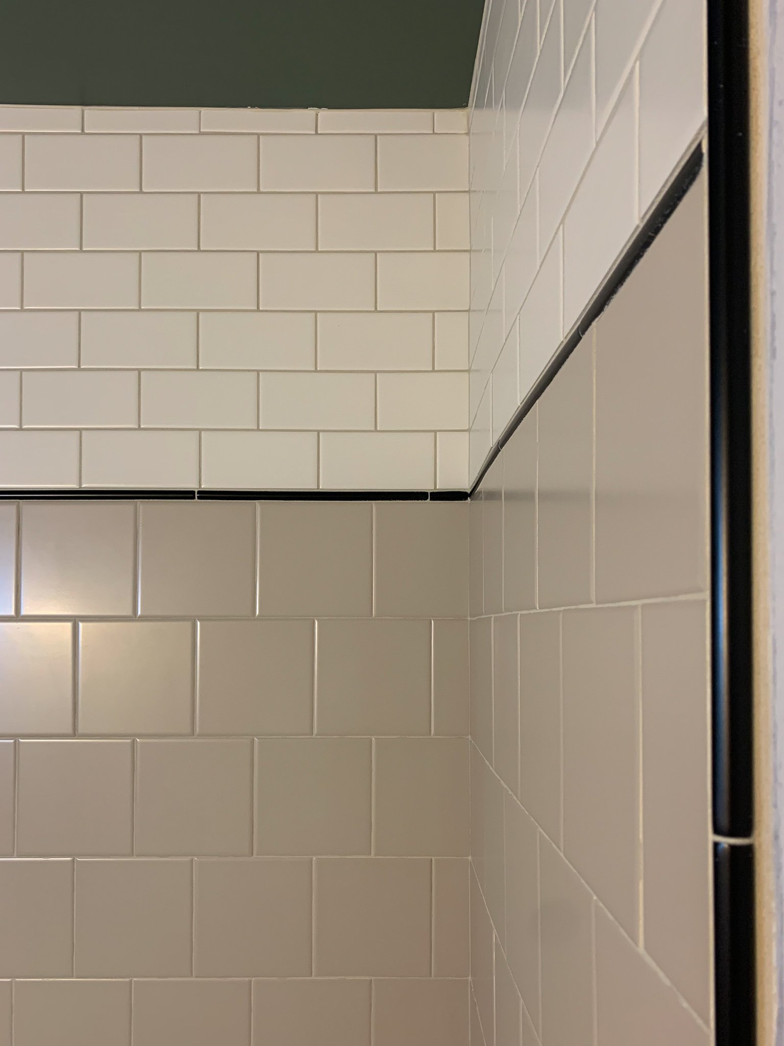 subway tile shower with tile patter of white, beige and black wtih a pencil tile edge trim