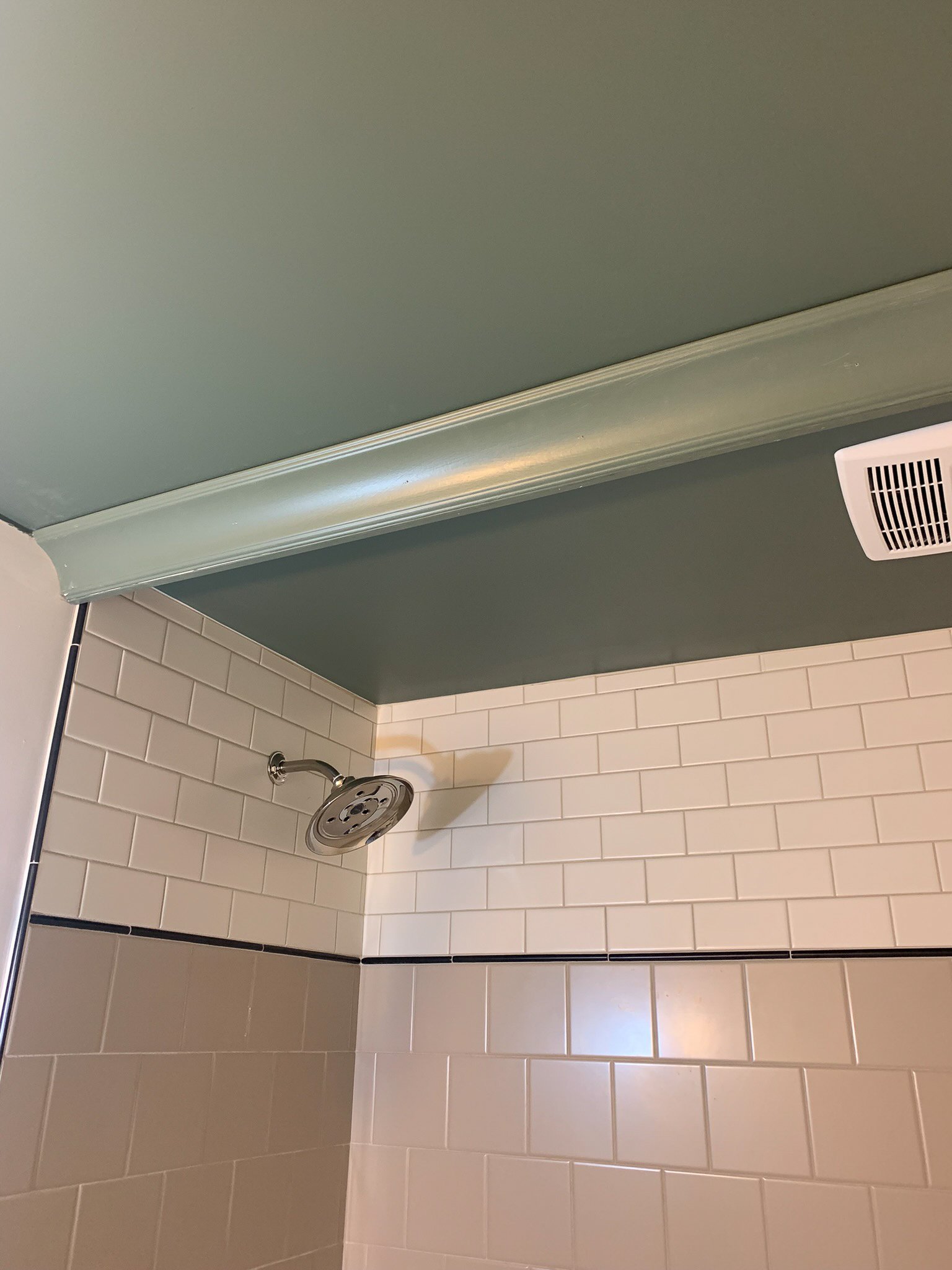 crown moulding installed in front of a shower as a valence, with subway tile shower in background