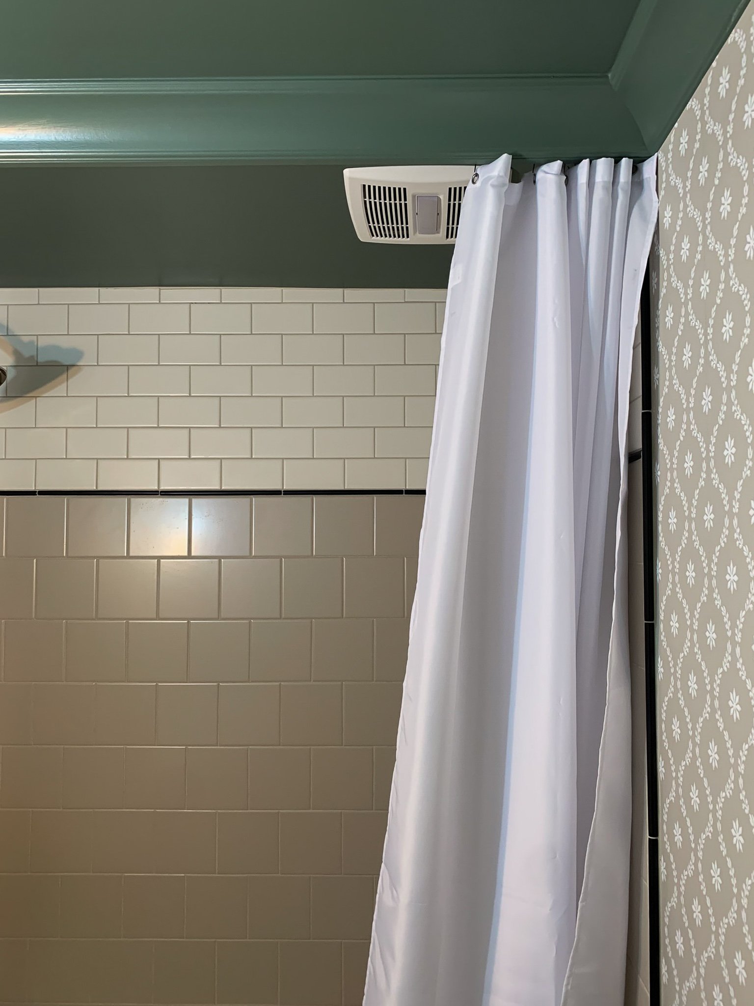 shower curtain on a ceilling mounted track that is hidden behind a crown moulding valence.  Subway tile shower in background