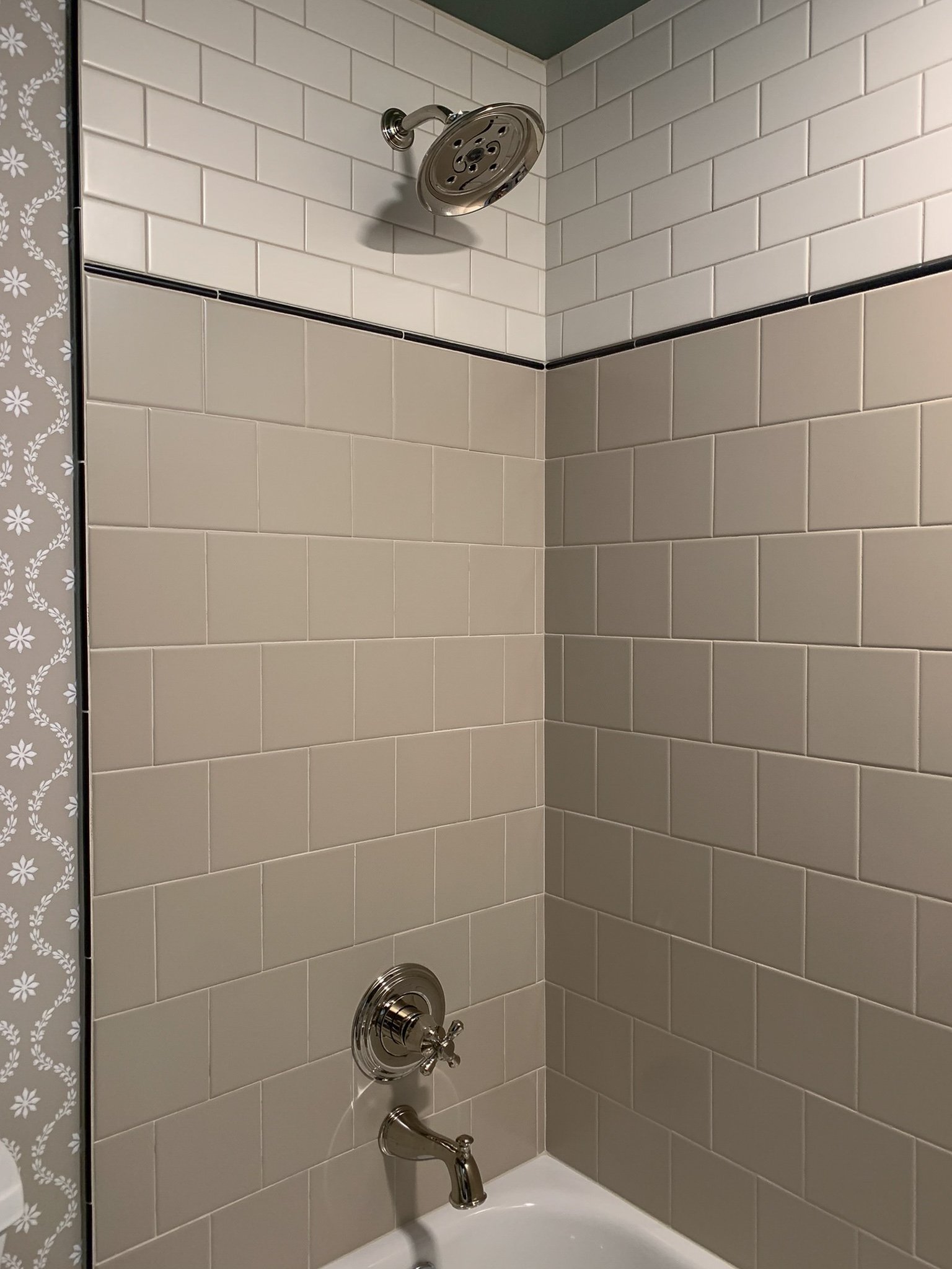 shower with subway tile pattern featuring beige 6x6 tile, a black pencil tile border, and cream coloured subway tile and polished nickel fixtures