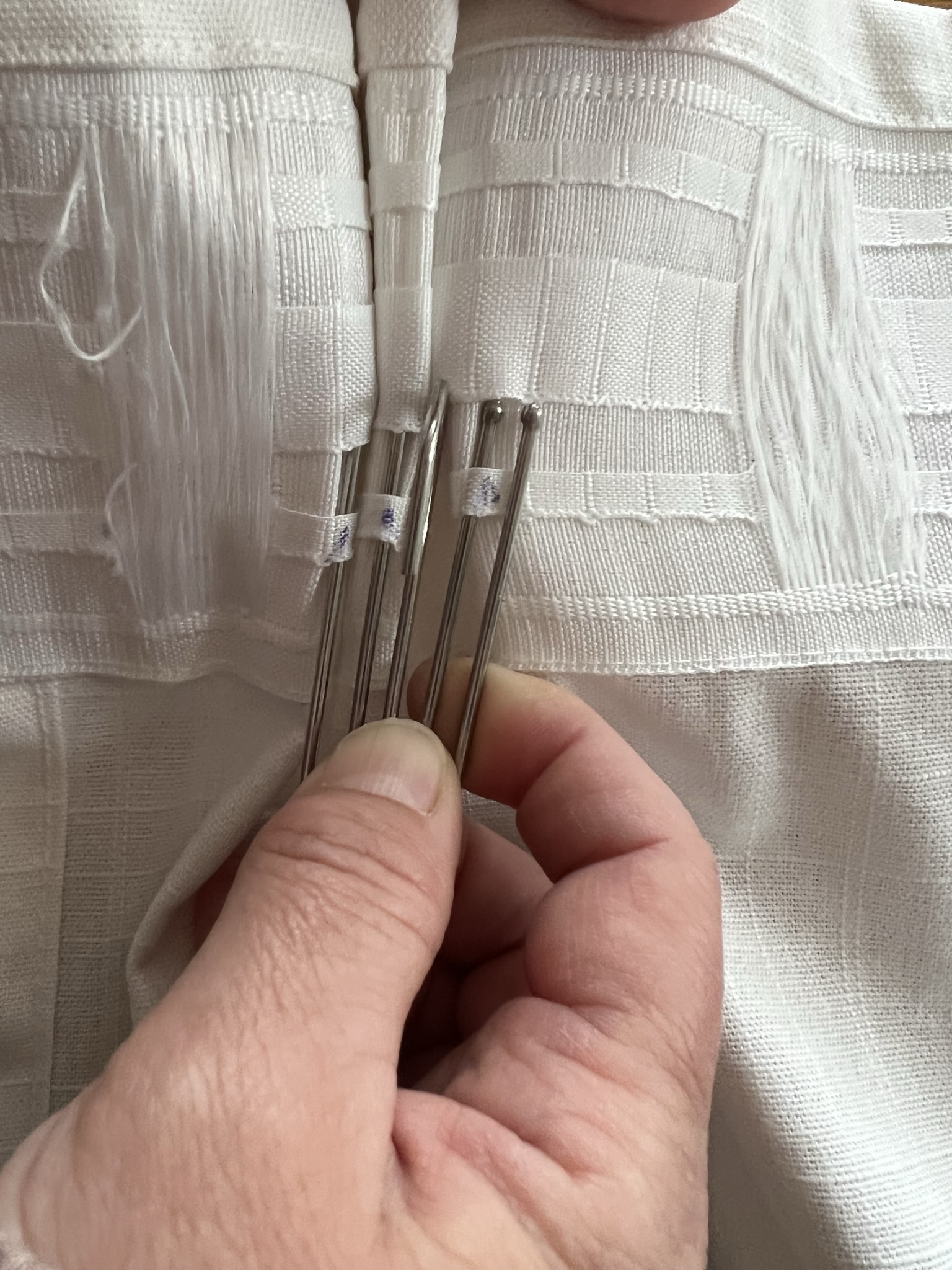 Inserting the third prong of the triple pleat curtain hook into the curtain tape
