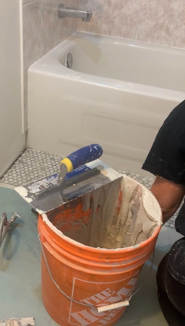 Tiling in progress showing a bucket with a fine toothed trowel 