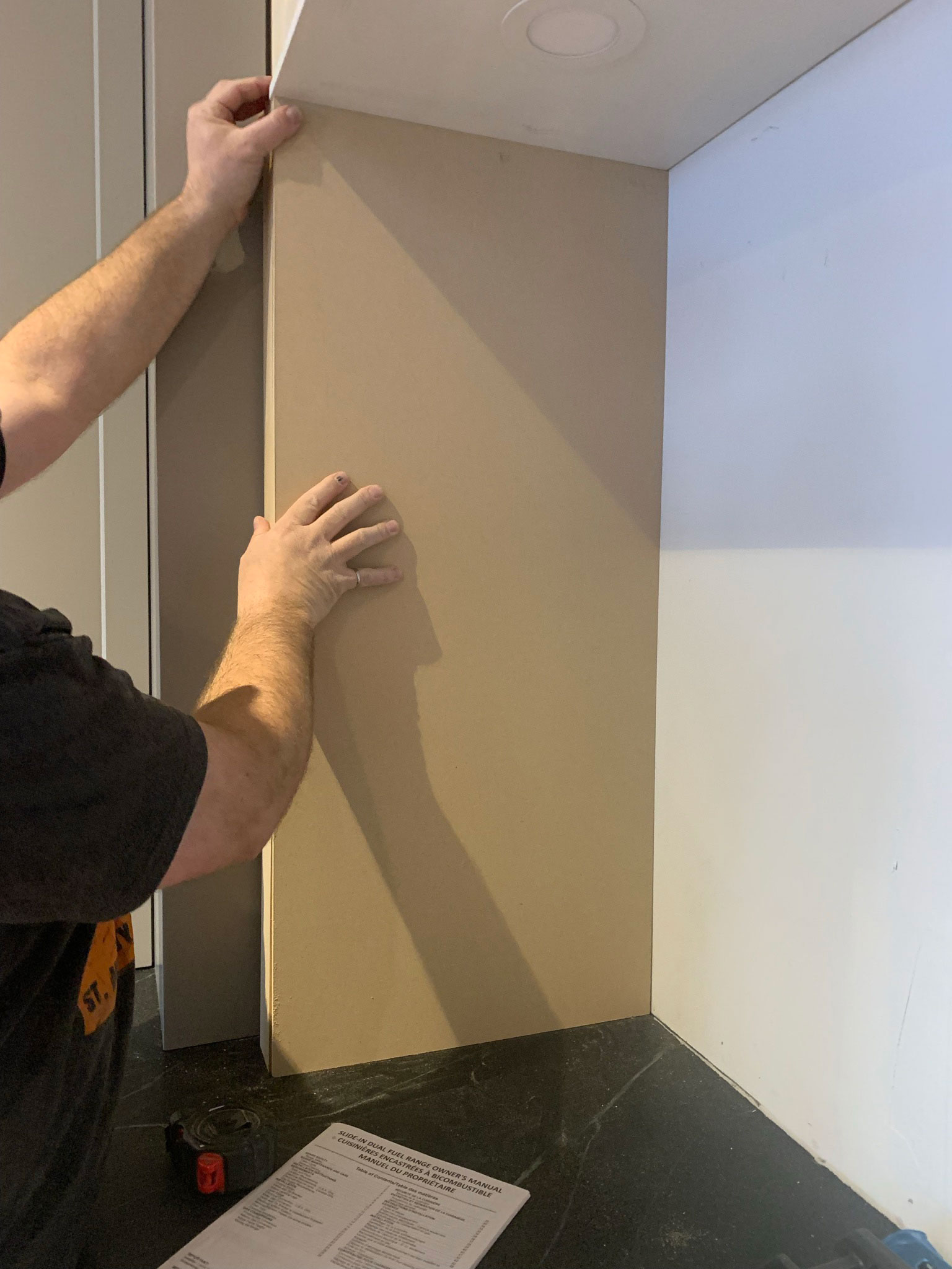 Holding a raw piece of MDF up on the side of the stove nook to fit in place