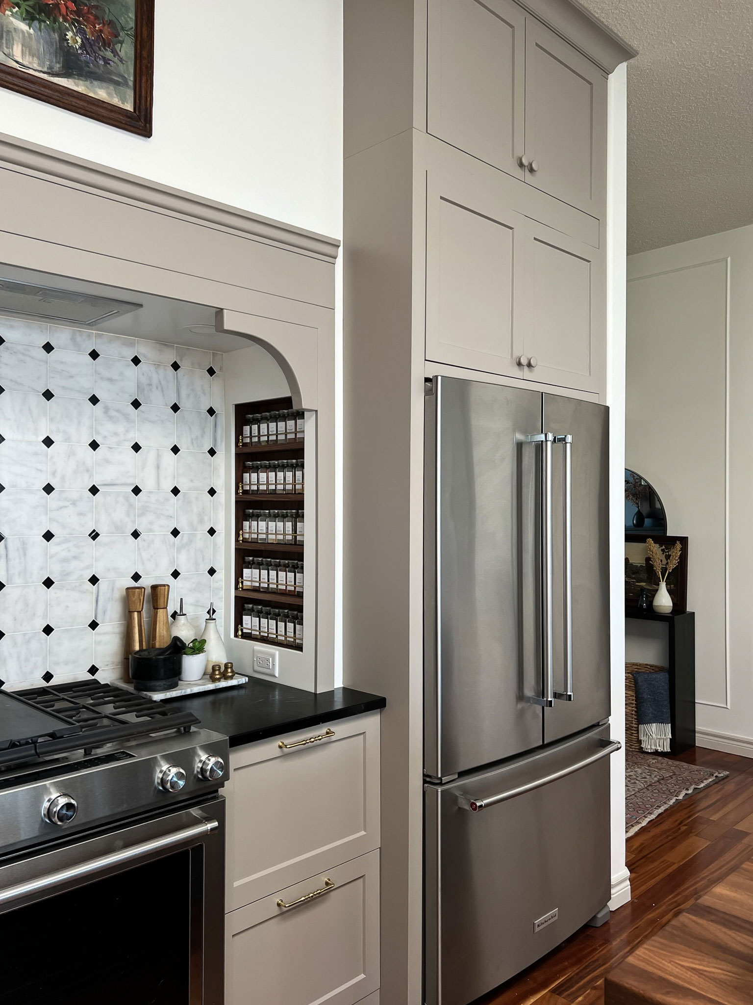 Kitchen with Fridge built with fillers all arounda nd deep cabinets over the fridge, beige cabinets with a stove nook beside the fridge and built in spice rack and marble tile