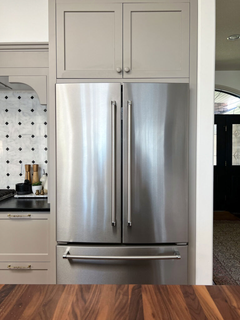 Kitchen with Fridge built with fillers all arounda nd deep cabinets over the fridge, beige cabinets with a stove nook beside the fridge and built in spice rack and marble tile