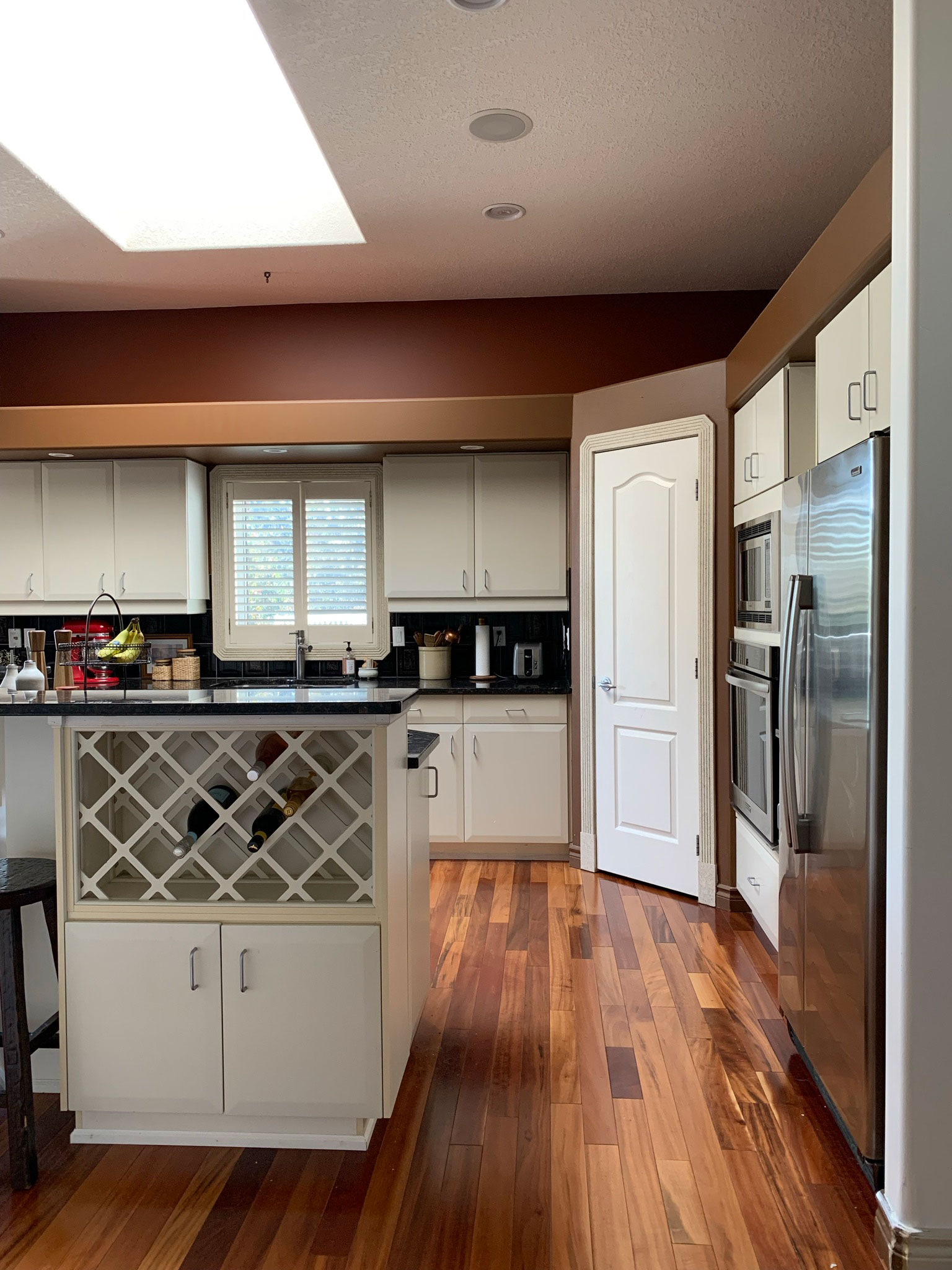 before image of kitchen with white cabinets, bulkhead over cabinets, corner pantry, raised eating bar, fridge sticking out past cabinets