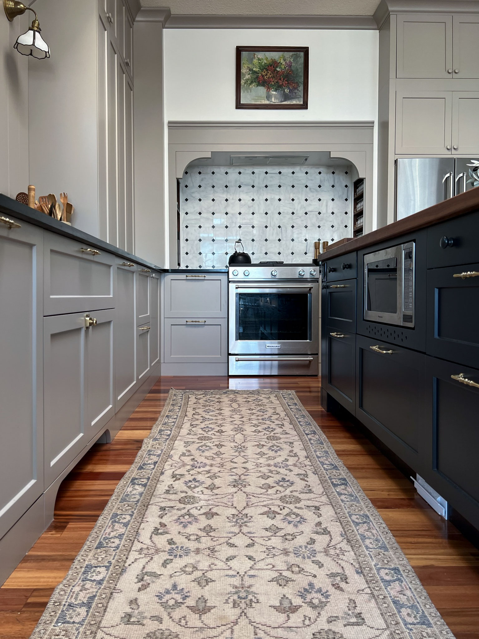 kitchen with beige cabinets and black island, vintage runner and a stove nook 