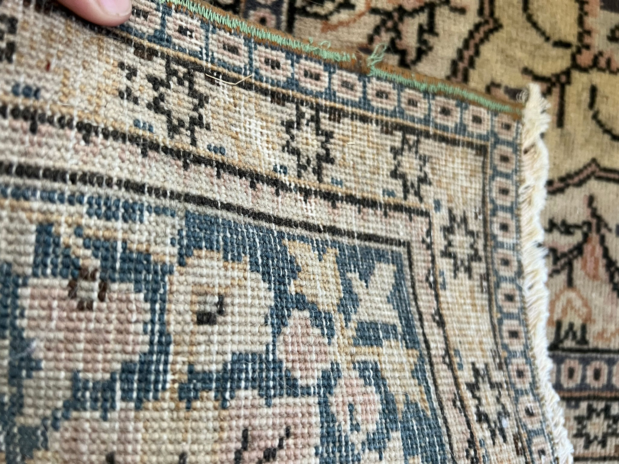 Close up of a wool vintage rug showing the back and the knots tied
