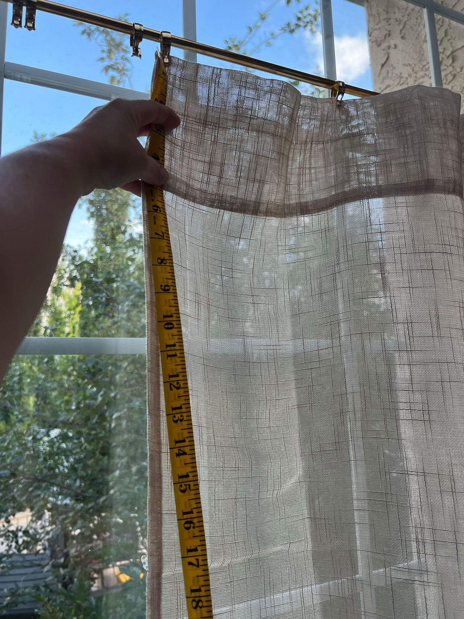 Holding a measuring tape up to curtains