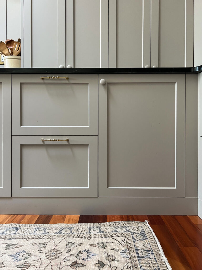 beige cabinets with drawers and doors and black countertop with flush toe kicks