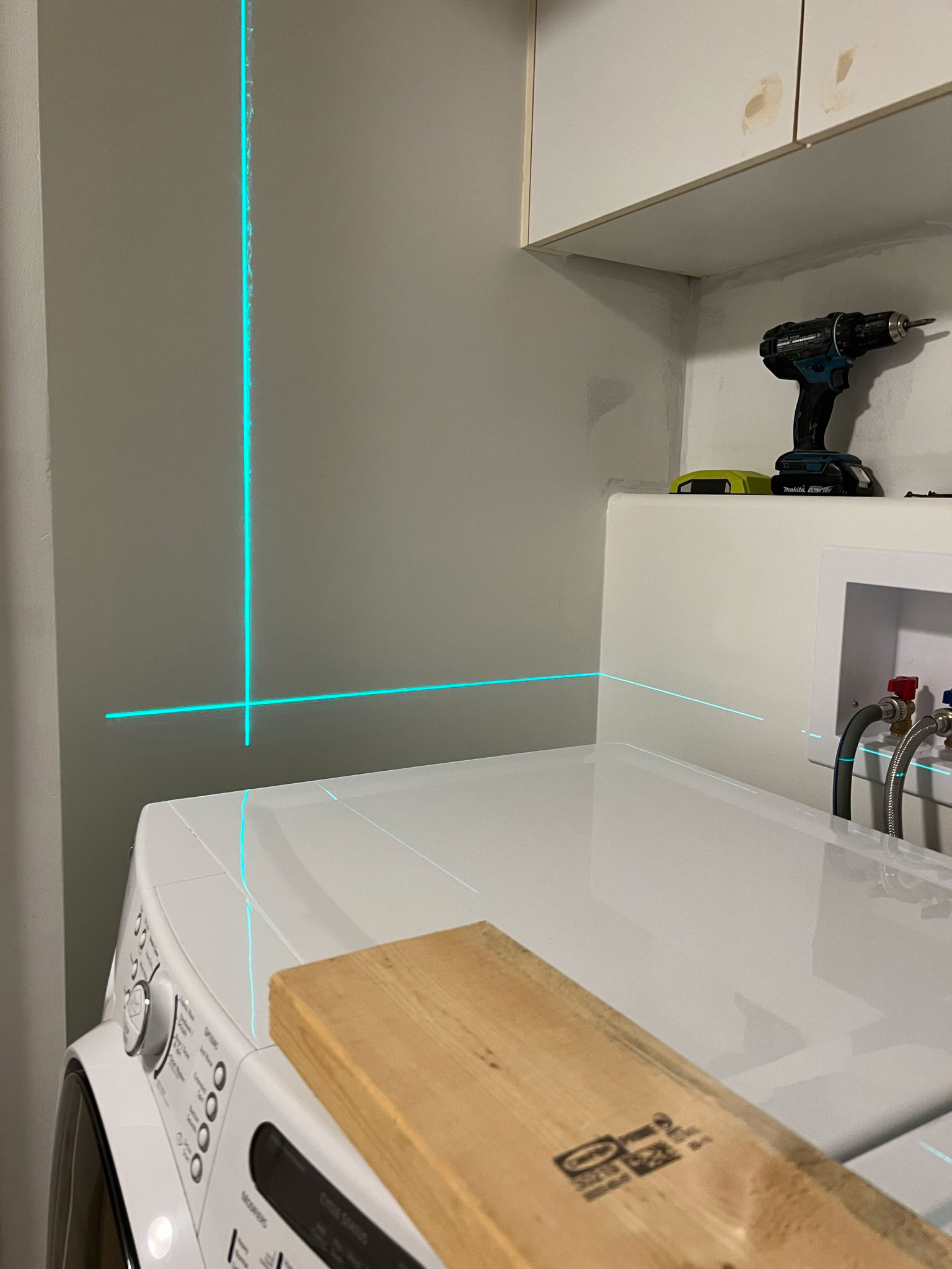 laser level projecting on the wall about 2" above the height of a washer and dryer in a laundry closet