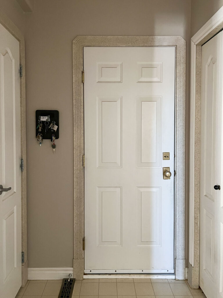 mud room before with beige walls and white door to garage