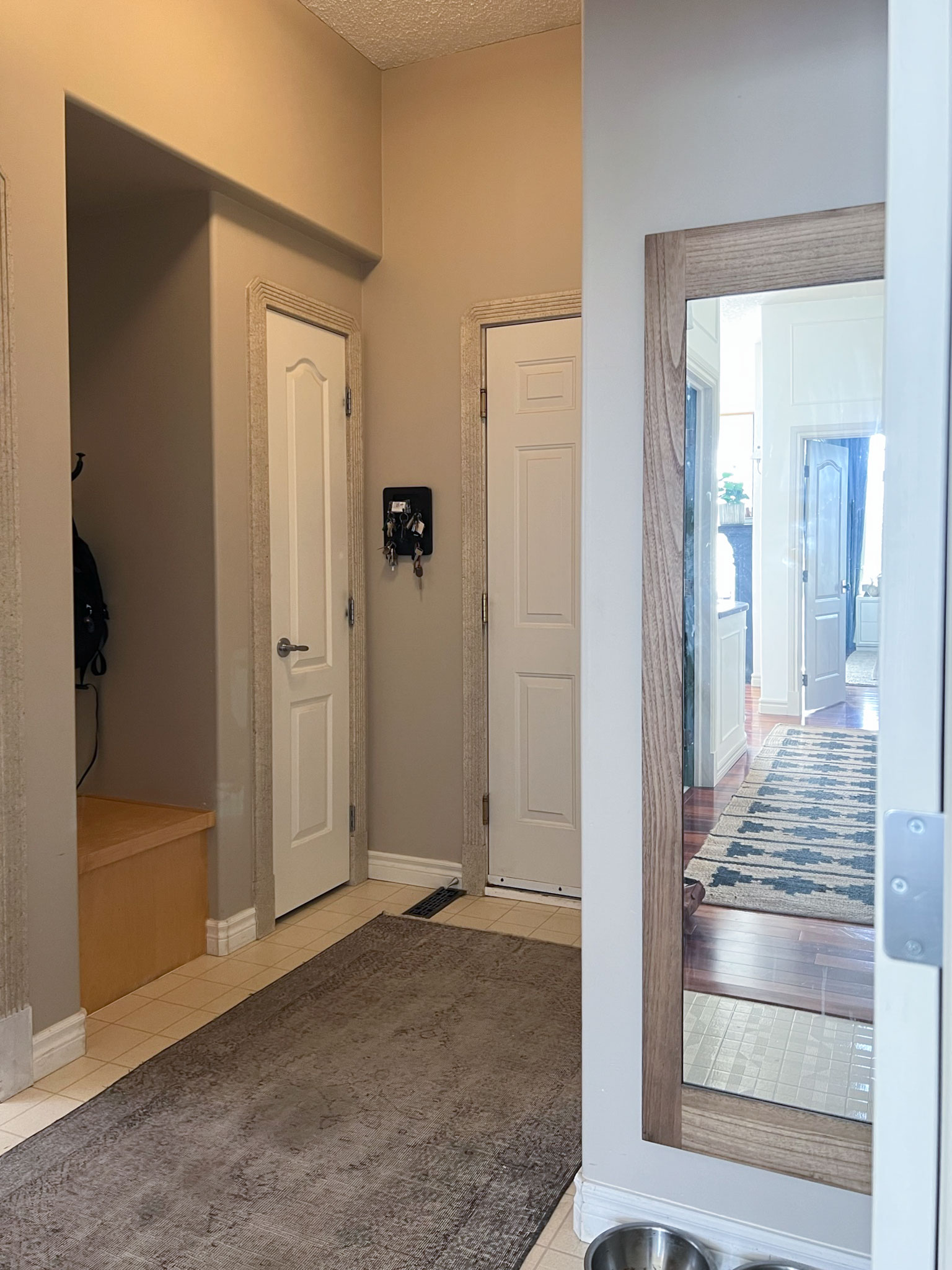 mud room with beige walls, skinny closet with small bench beside, linoleum floor.