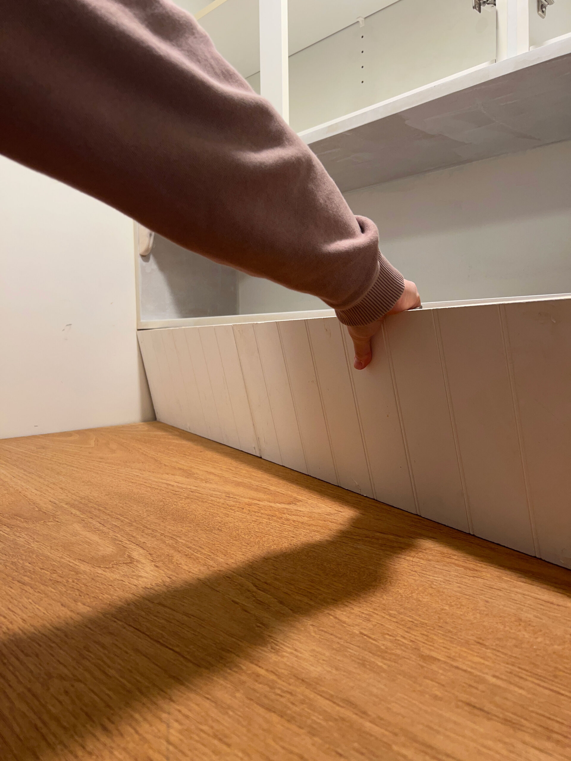 placing a beadboard backsplash between DIY wood laundry room countertop and underside of the cabinets and shelf above