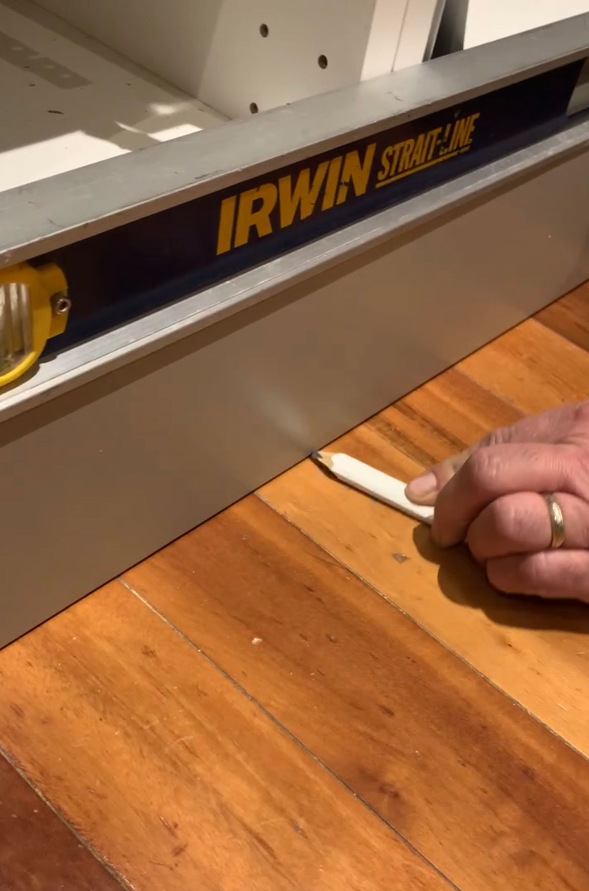 running a pencil along the floor to scribe the bottom of the cabinet toe kick