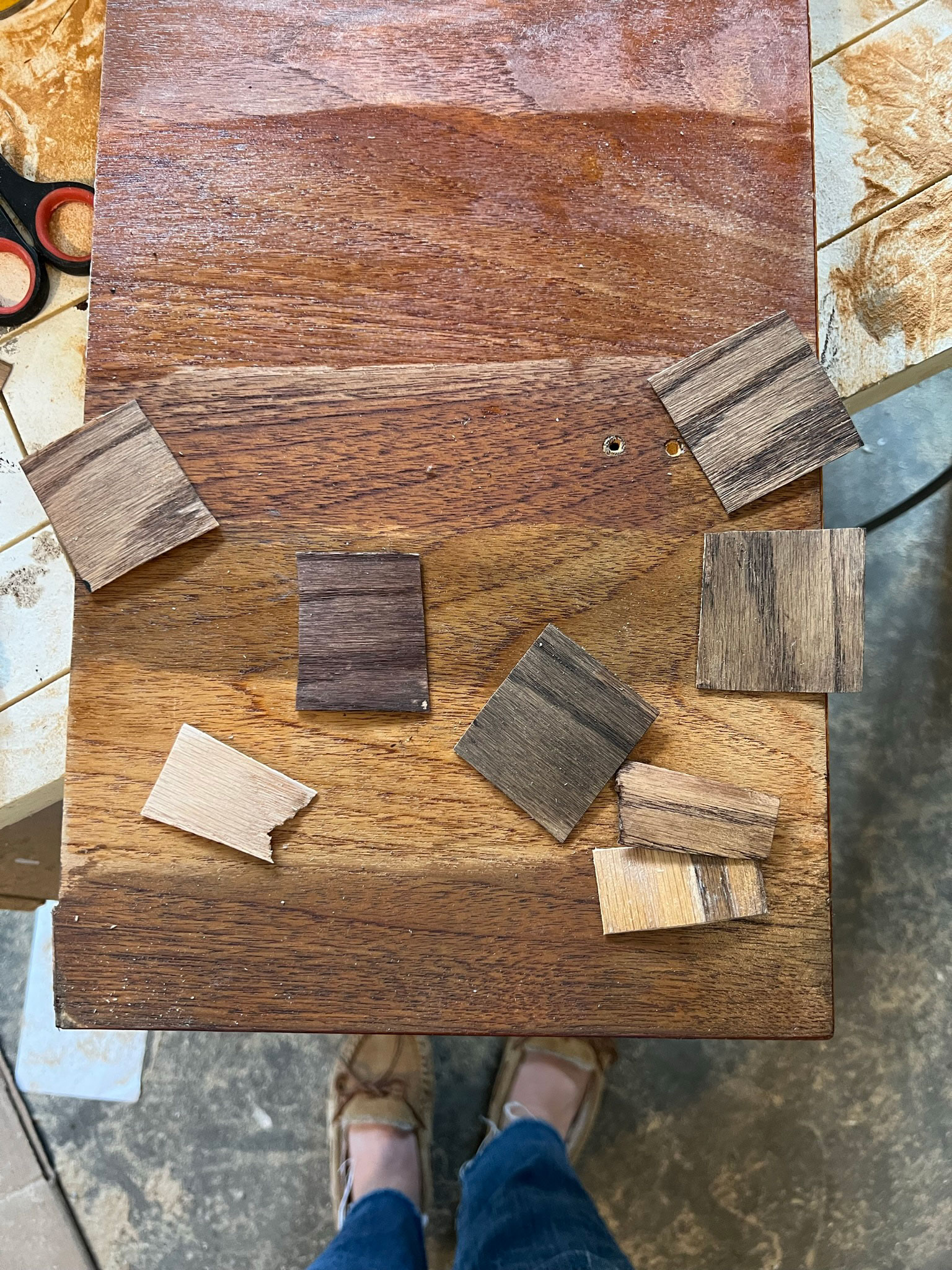 wood surface with several different stains on it, and then pieces of veneer with several different stains on them, to test the final look of the DIY laundry room countertop