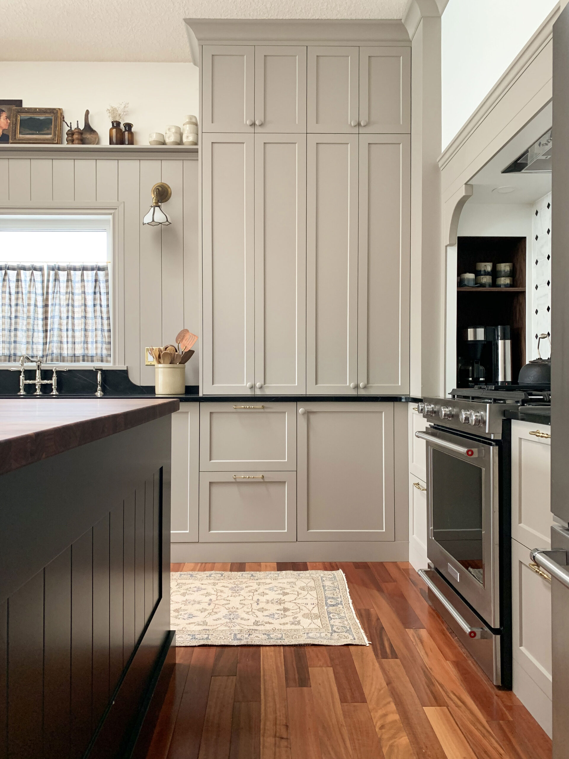 beige kitchen with countertop cupboards, nook in the corner, black soapstone counters, black island, ,wood floor, vintage runner