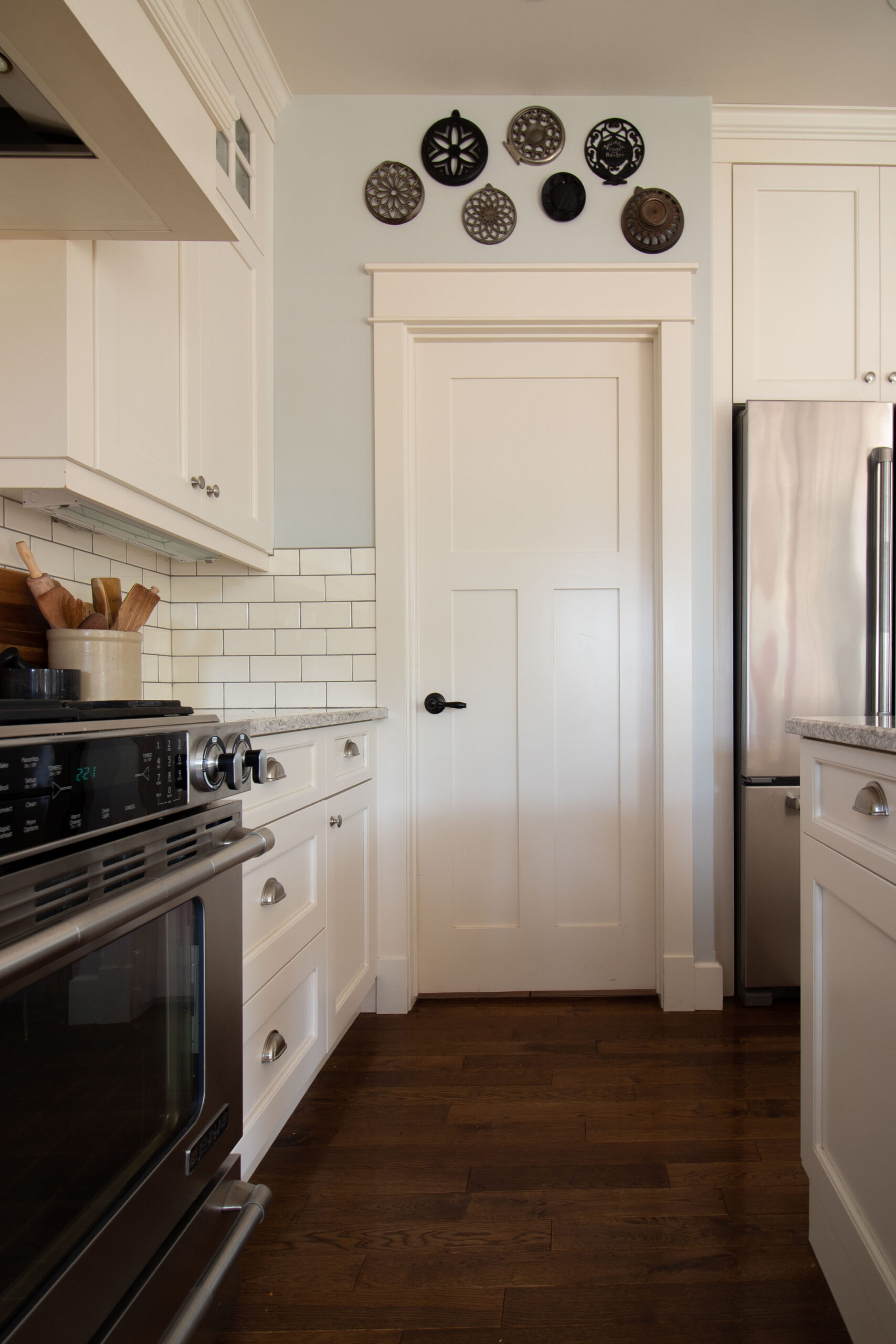 white kitchen with blue grey walls, subway tile with a corner pantry door