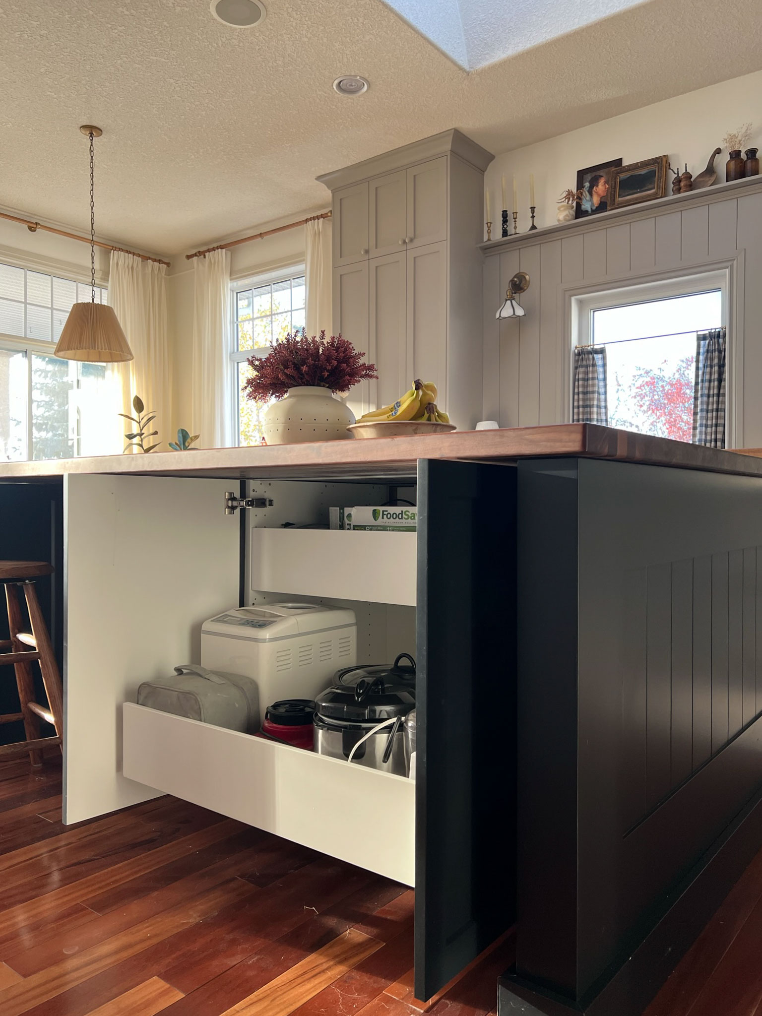 cabinets in the back of an island with sliding drawers to house appliances with drawer partially pulled out