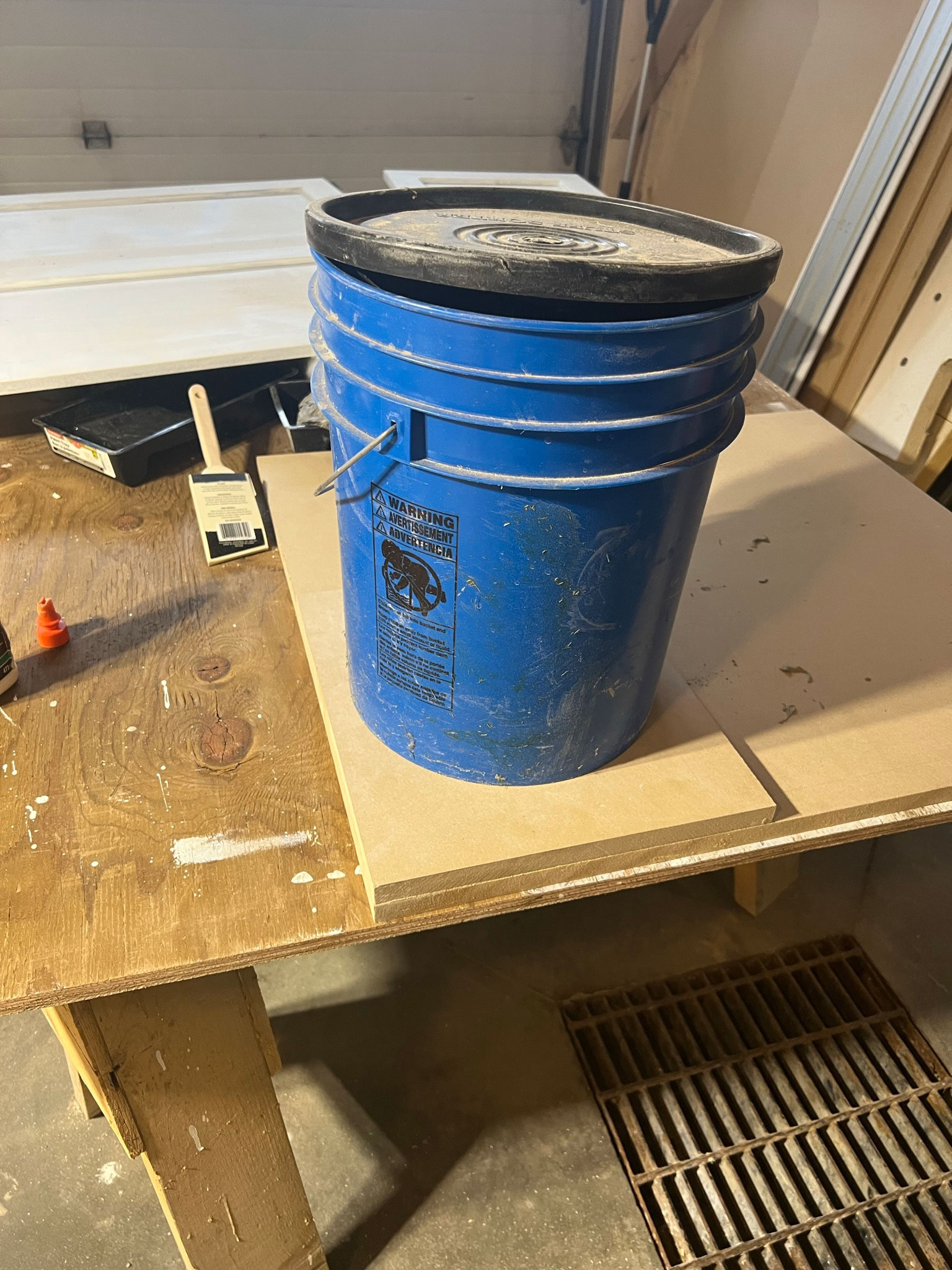 two pieces of MDF with a large heavy bucket on top