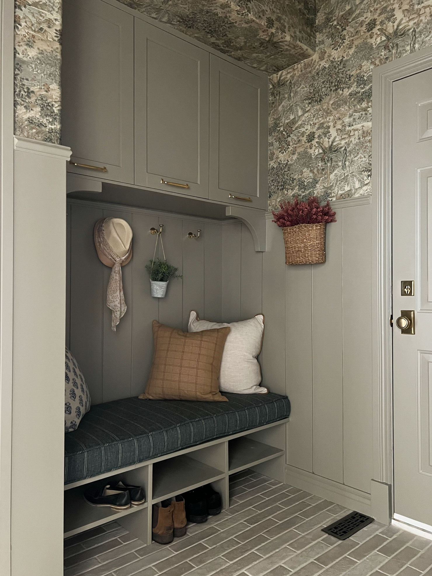 bench seat in mudroom with bench cushion, cabinets above, shiplap walls, shoe shelves below a bench seat with cushion