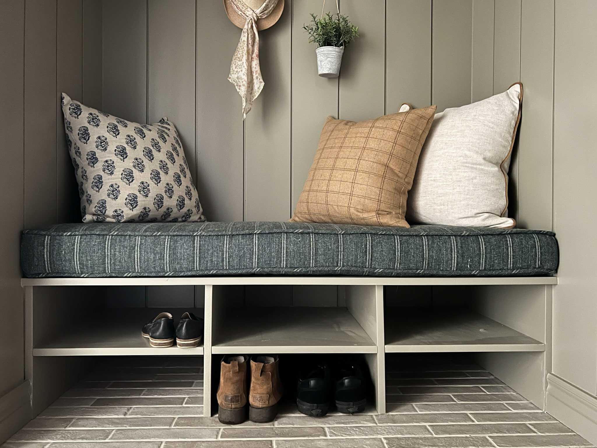 bench seat with shoe shelves below with navy stirped cushion and three pillows