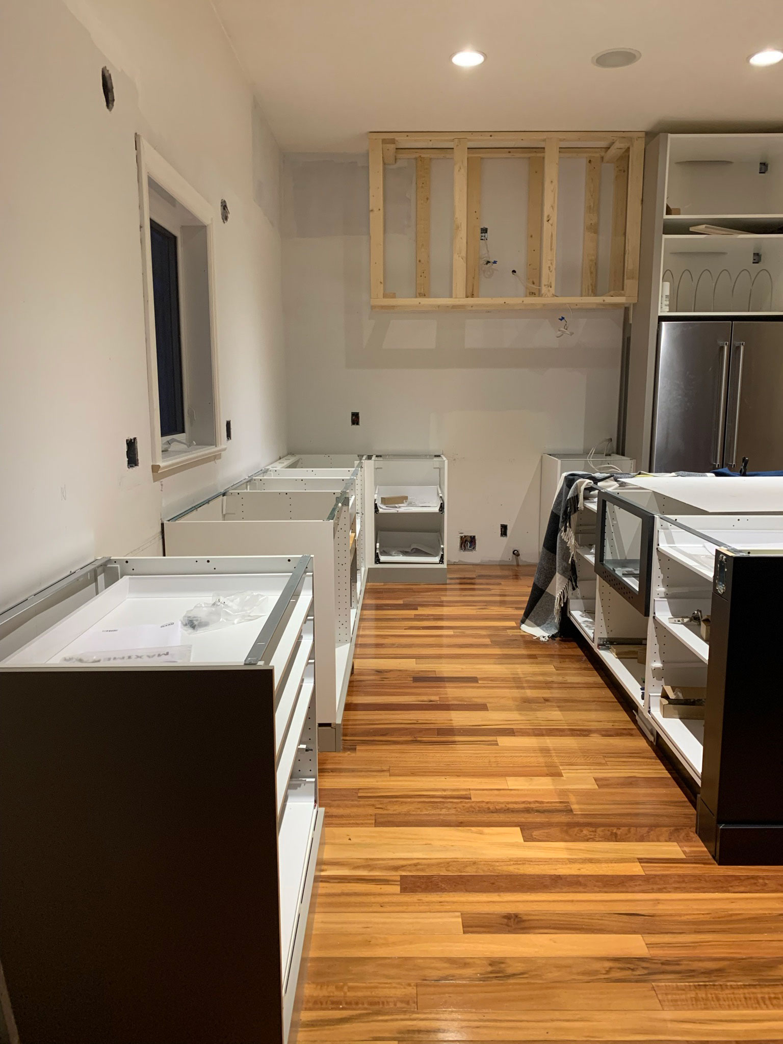 kitchen under construction with hood pframed and no countertops, cabinets installed