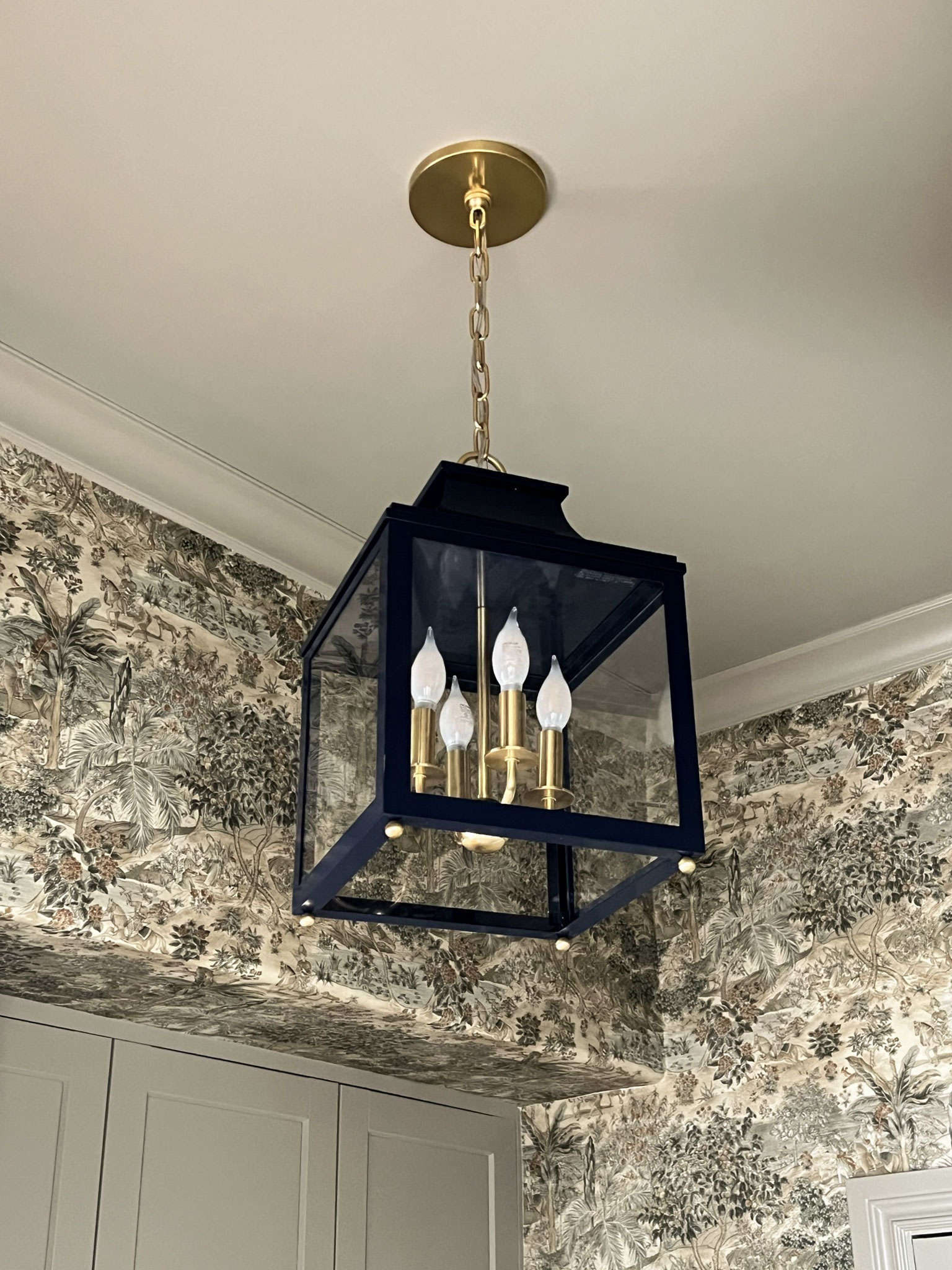 close up of lantern with navy blue and brass finish, with scenic wallpaper in the background