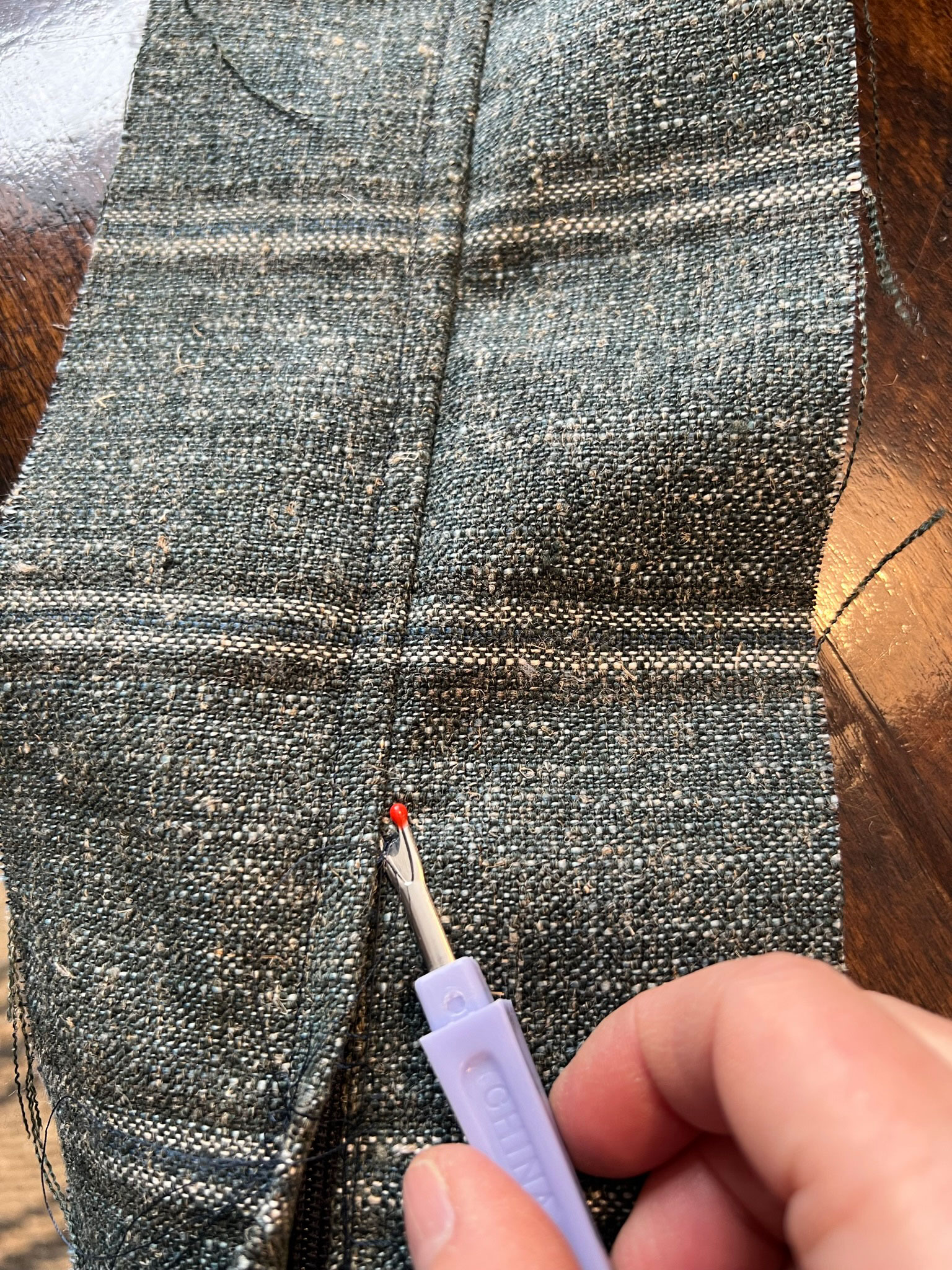 Using a seam ripper to remove a stitch on flap of fabric