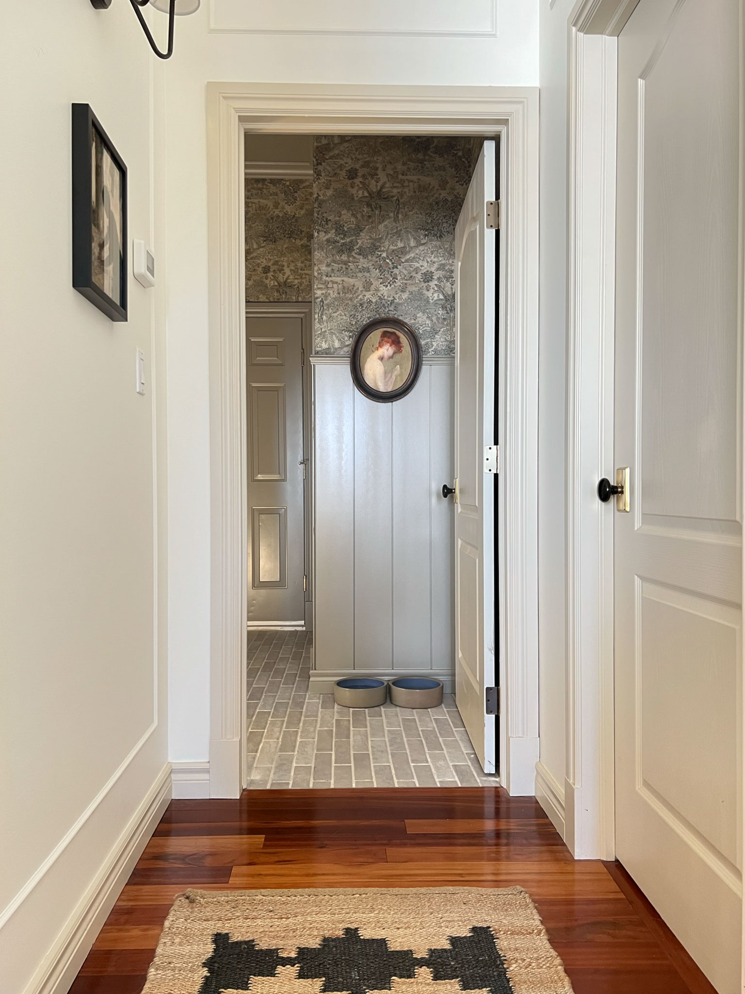 mudroom veiw from hallway with a portait on the wall and shiplap and wallpaper in view