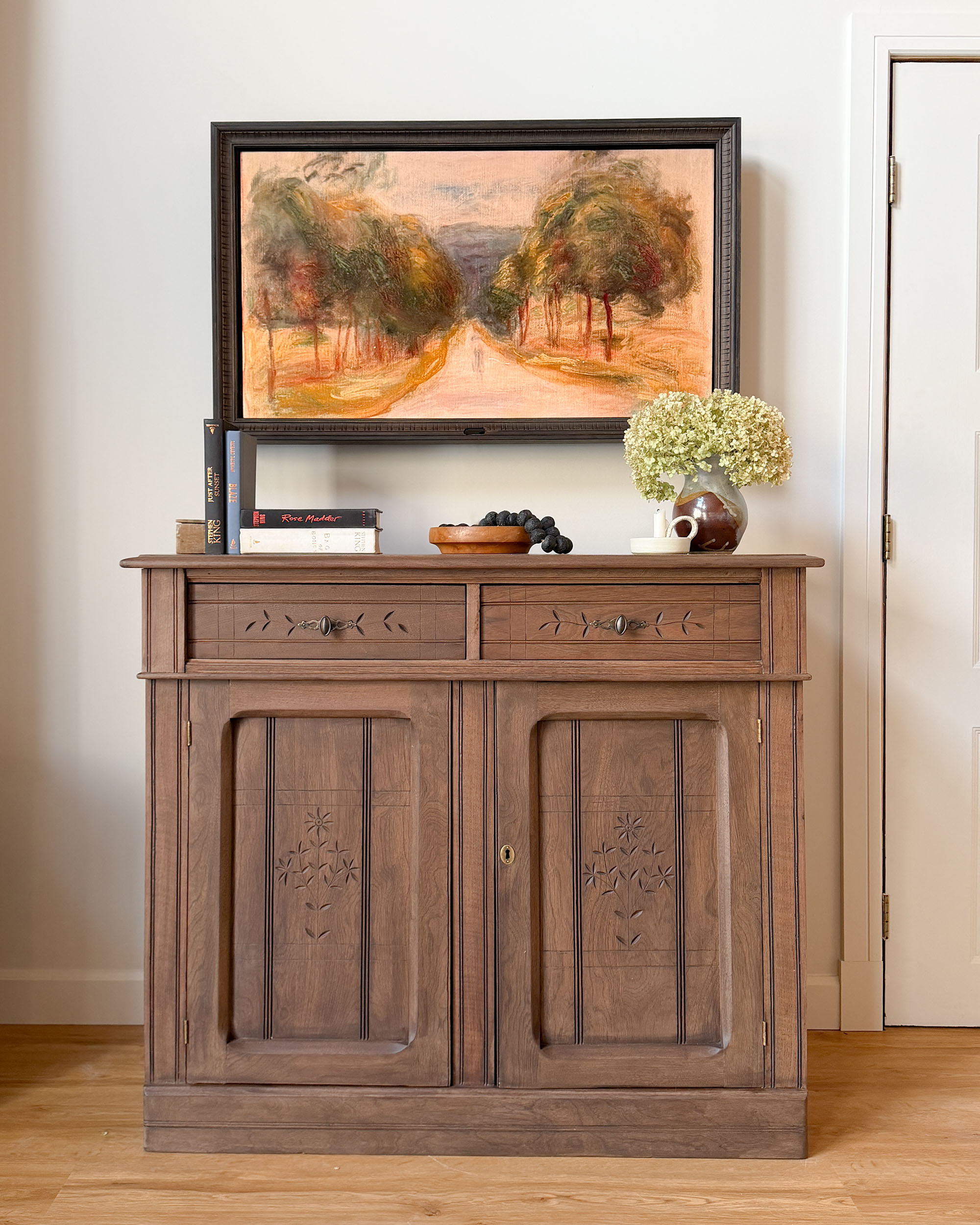 Framed TV over an antique piece