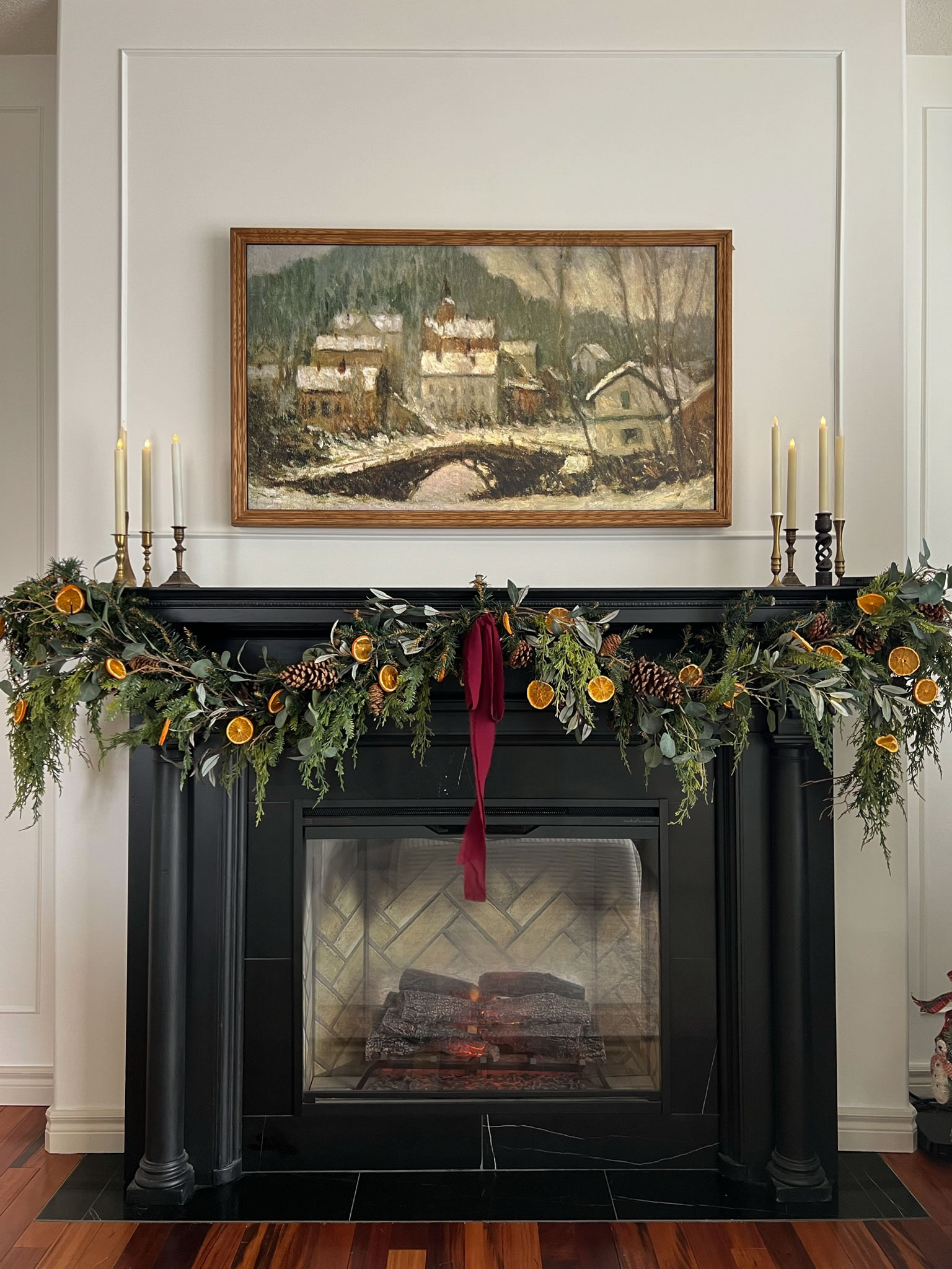 black fireplace with framed TV above with holiday garland