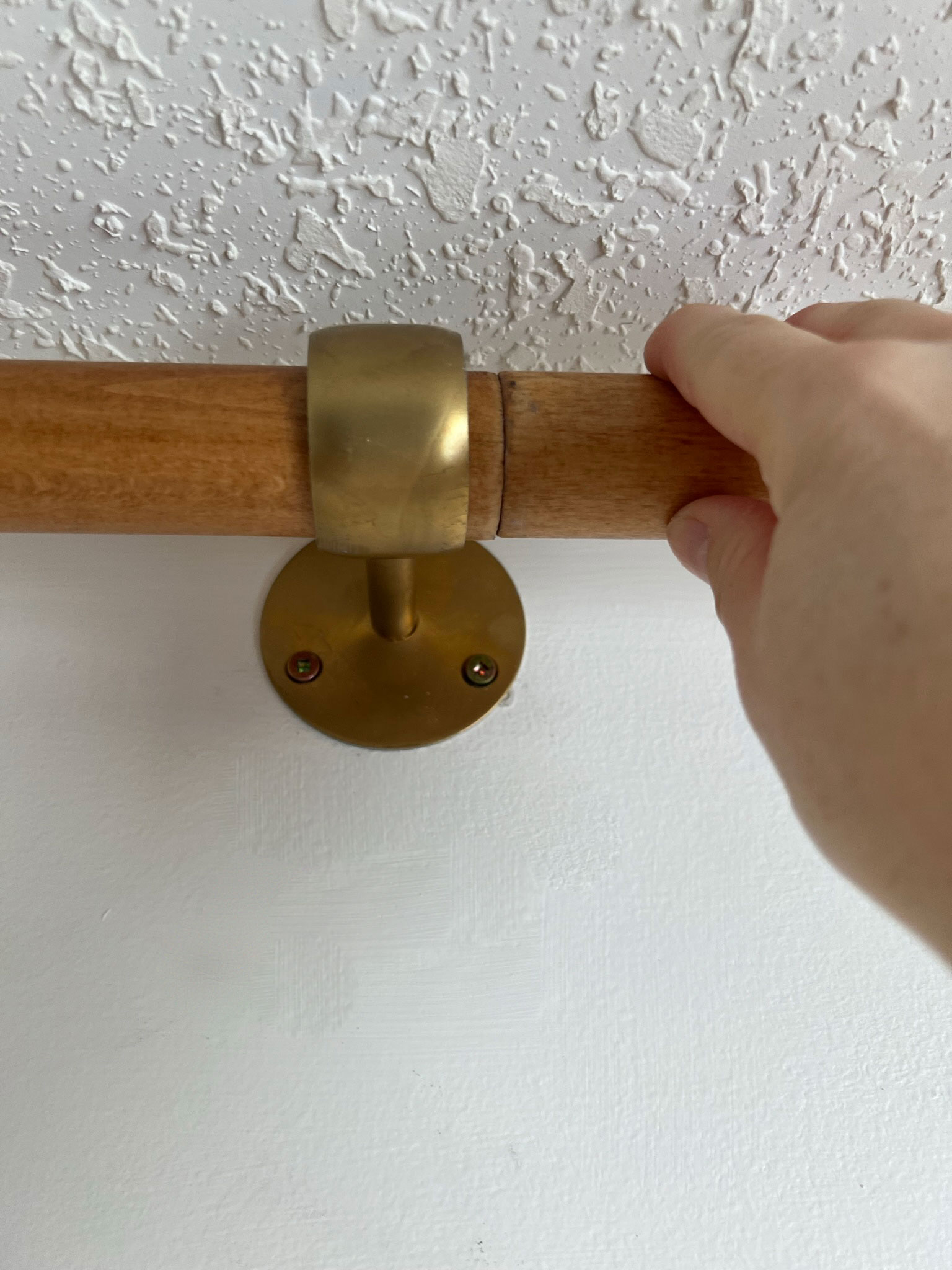 holding a wood rod that is going through a brass bracket showing where they are connected
