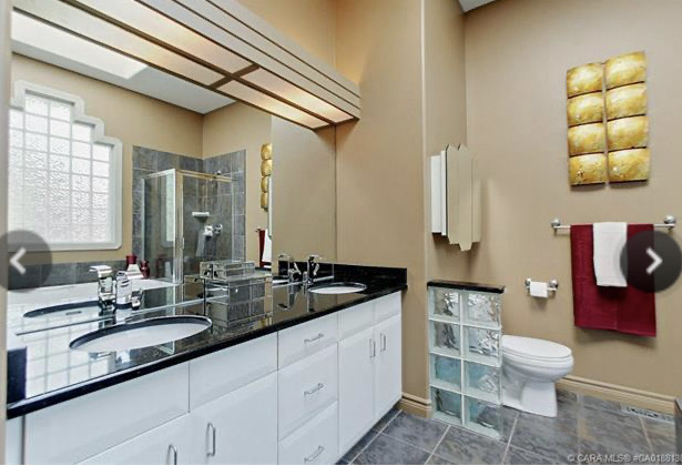 ensuite bathroom with white cabinets black counters and boxed out light and glass block