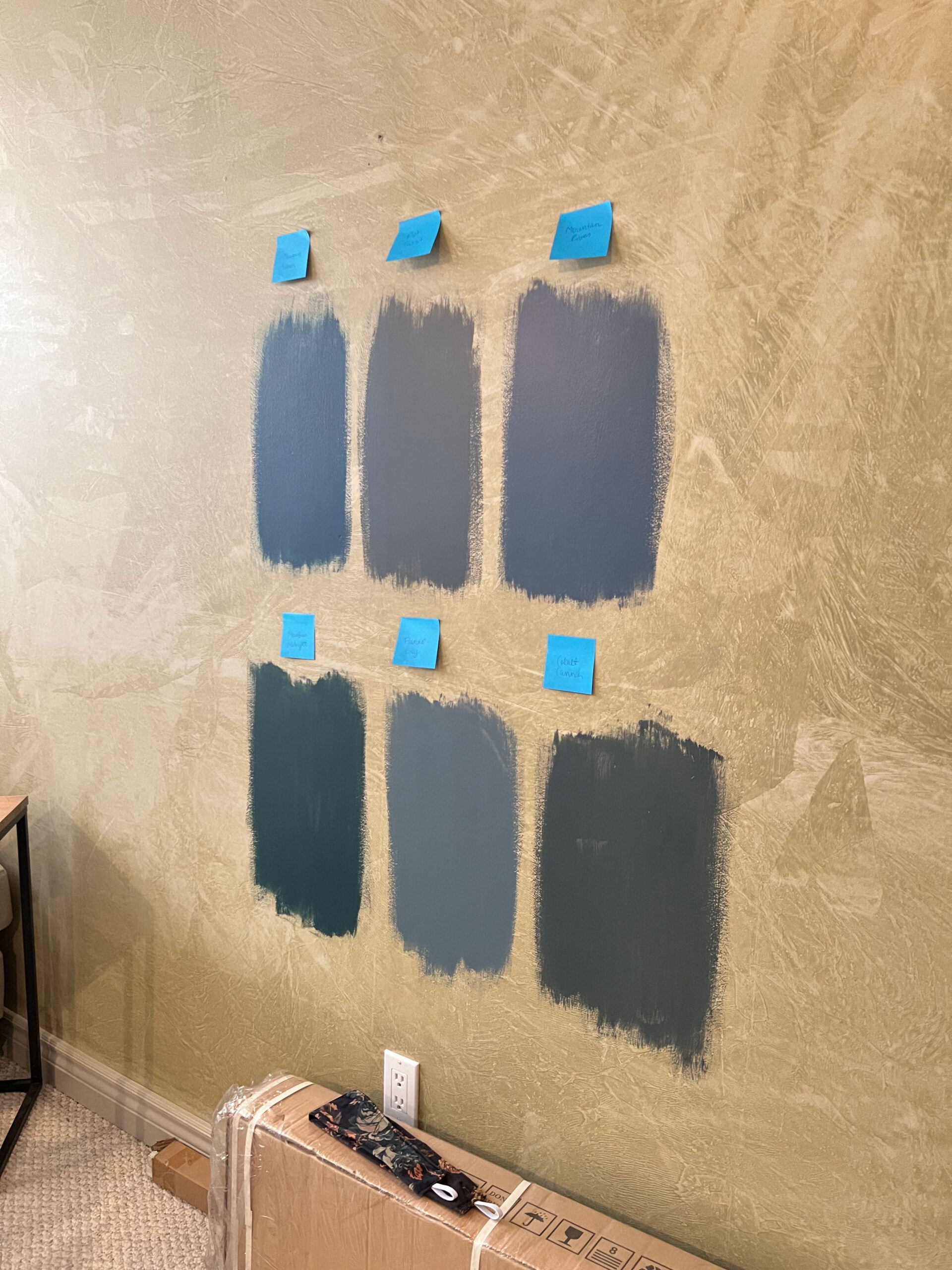 paint swatches on the wall testing blue green paints for the moody media room makeover.  Paint is the most budget friendly option for changes