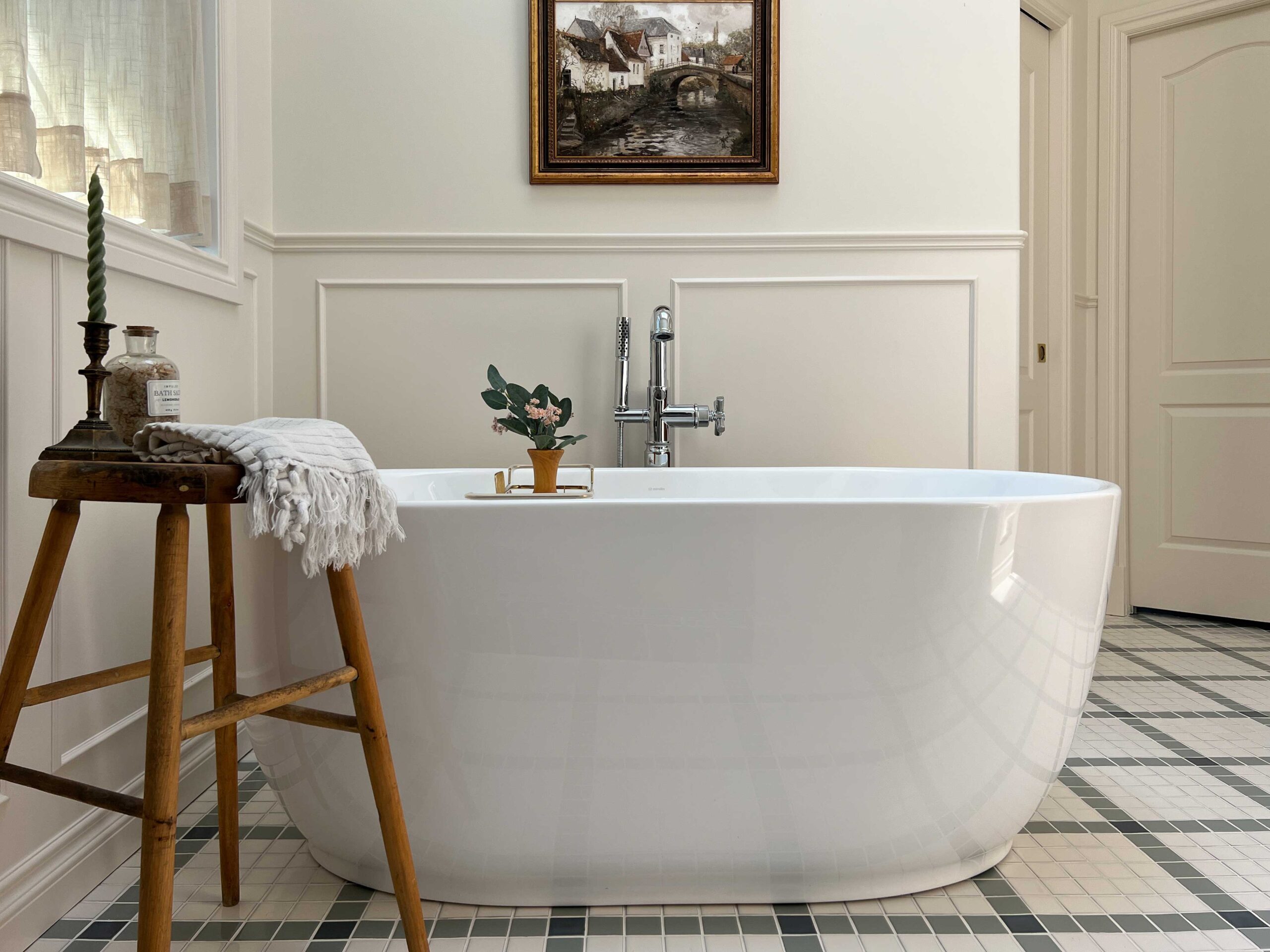 freestanding bathtub with antique wooden stool, checkerboard floor, beige walls