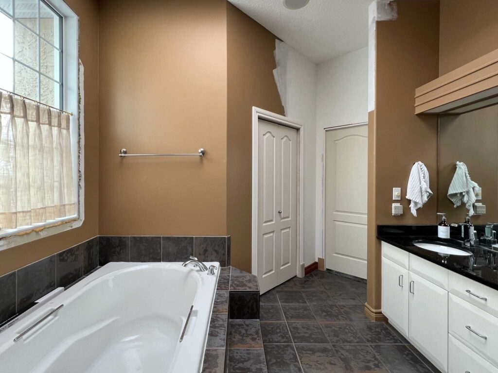 90's bathroom with large grey tiled tub, corner shower, glass block partition, brown walls