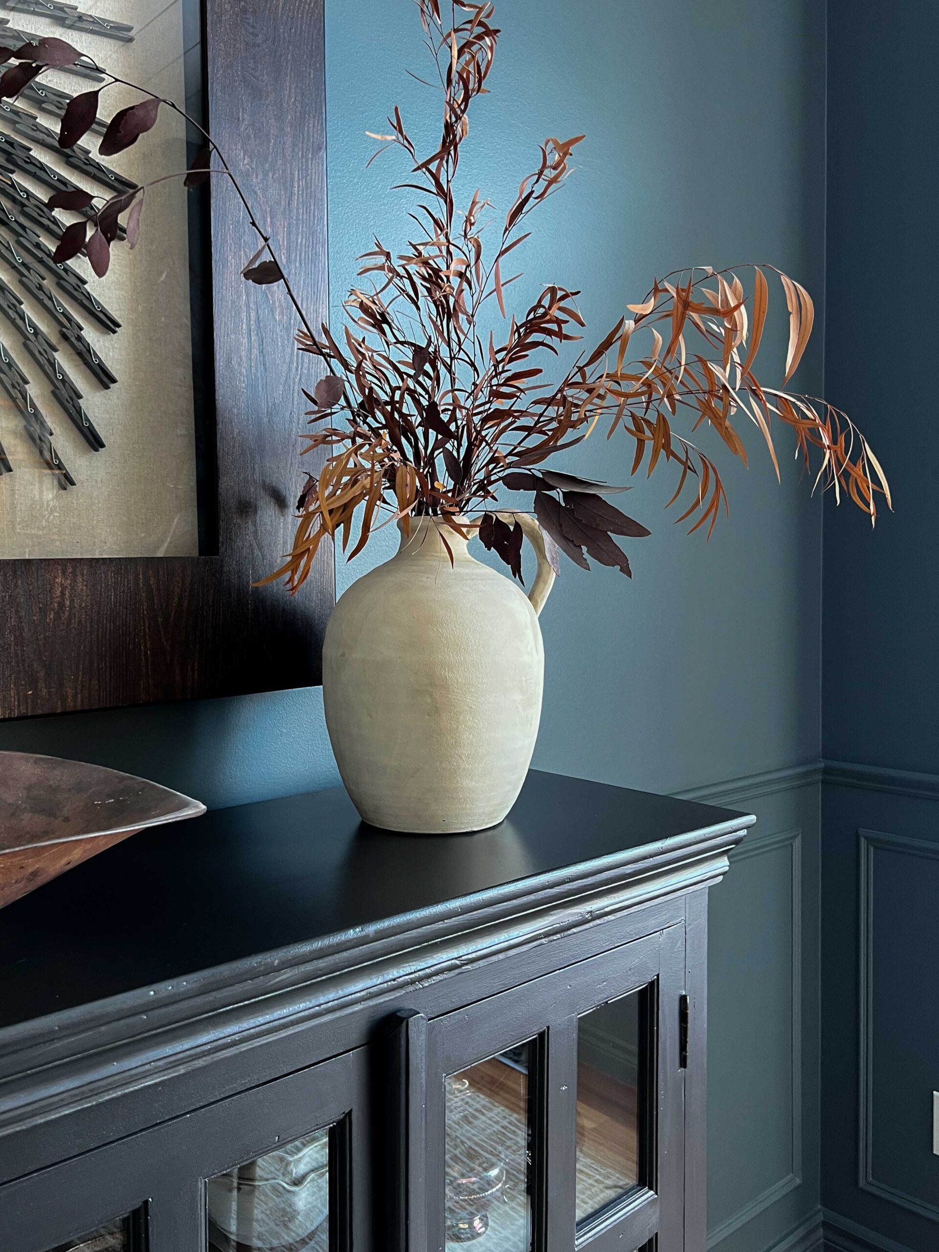white textured vase on console with branches in it