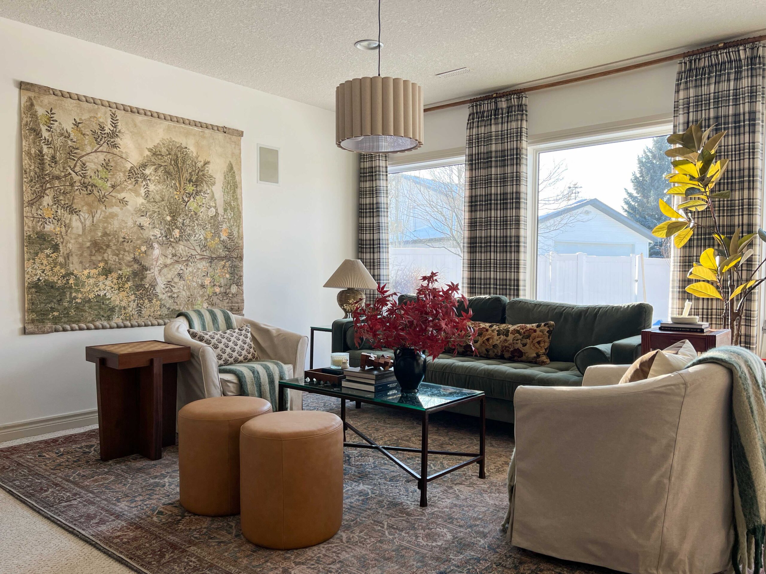 living room with plaid curtains, vintage style rug, white walls, tapestry on wall, and scalloped linen light fixture