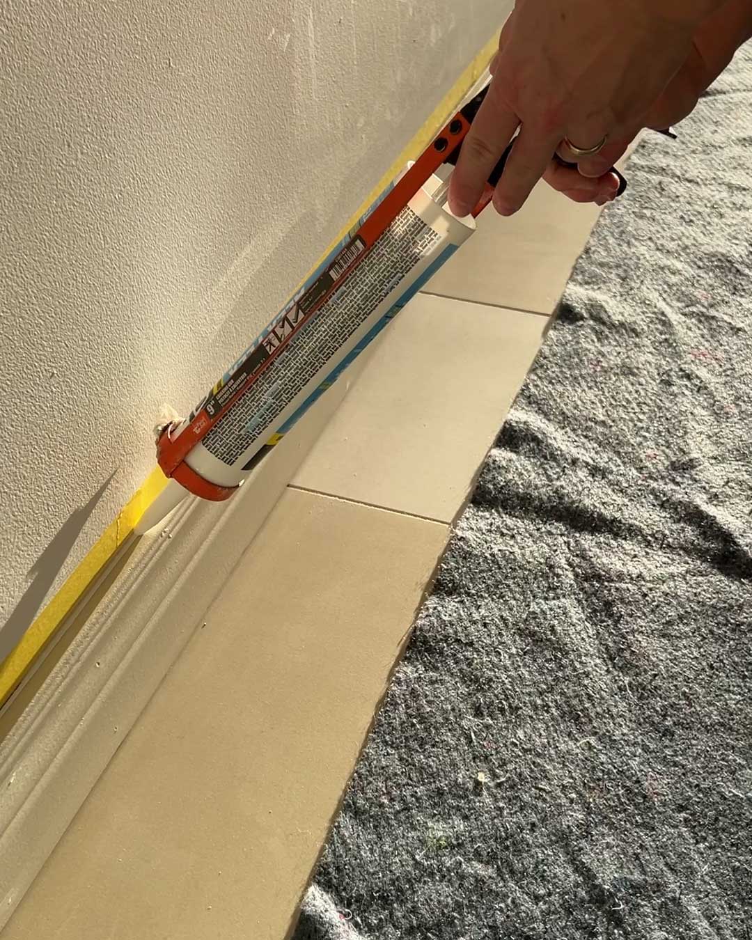 adding caulking along top of baseboards