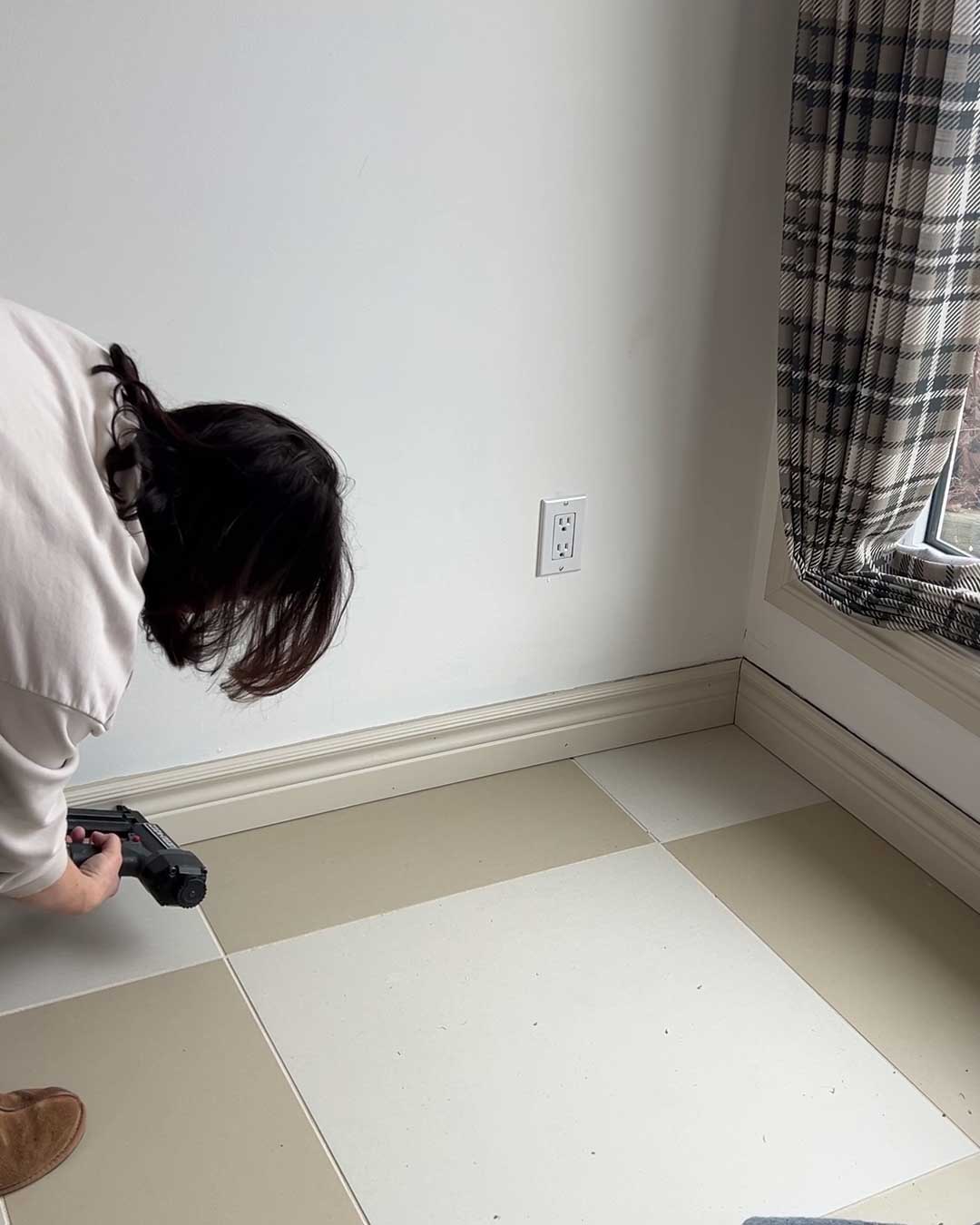 nailing baseboards on wall with a nail gun
