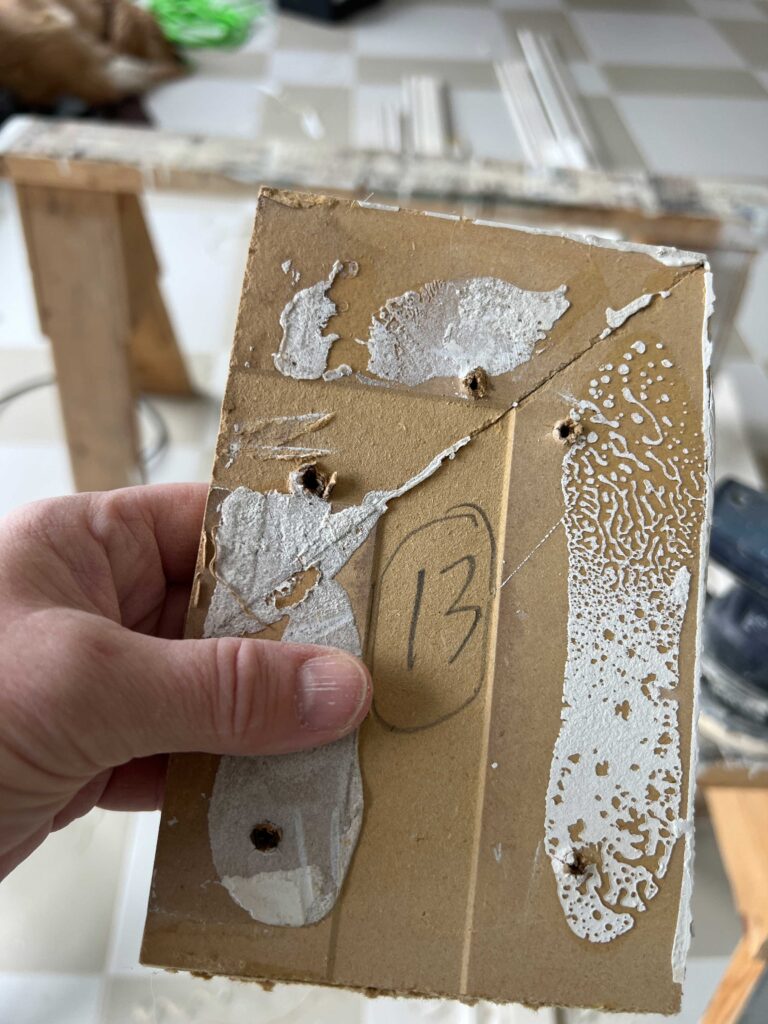 holding piece of baseboard with number on it