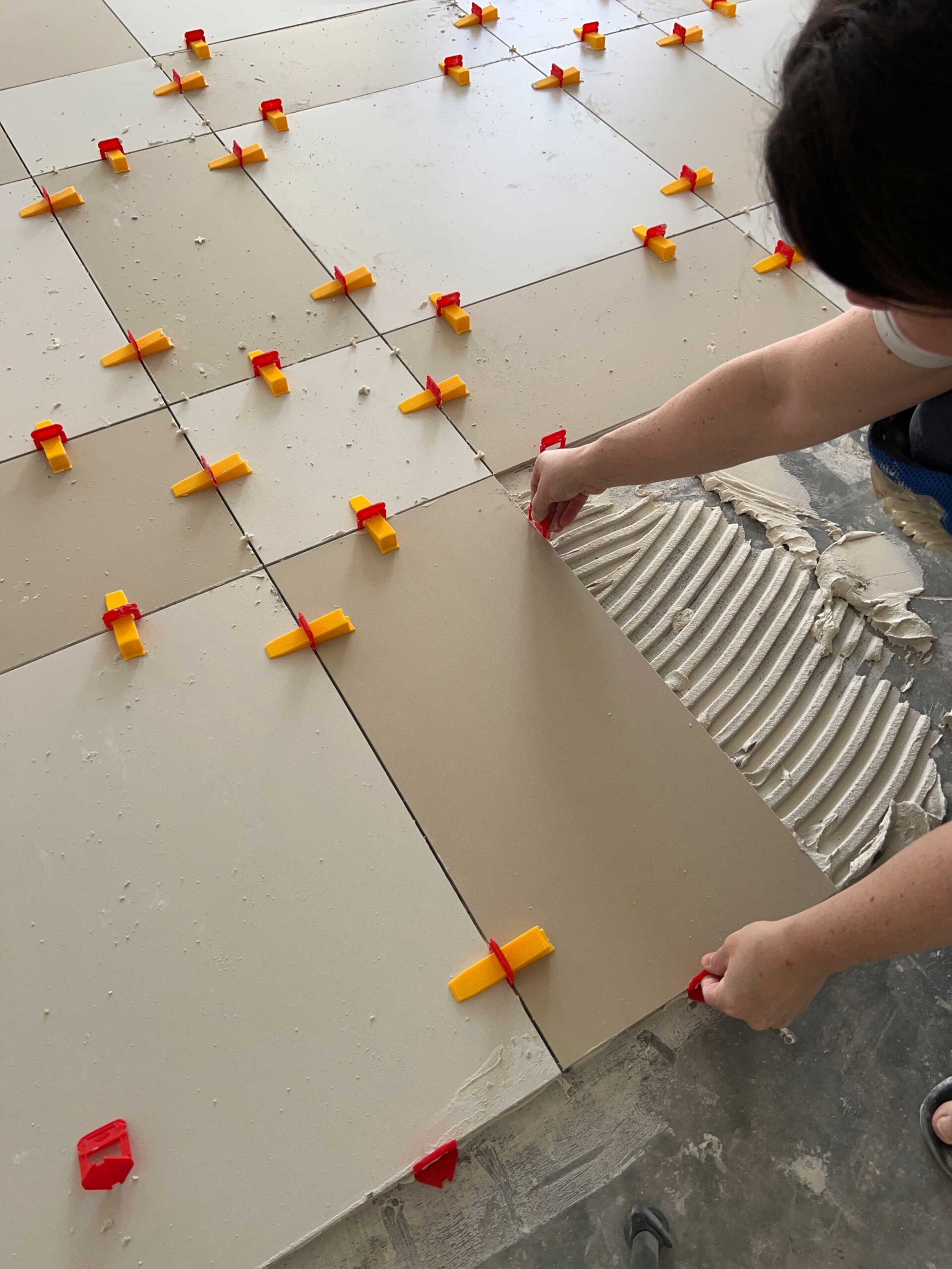 woman putting in leveling spacers on edges of tile