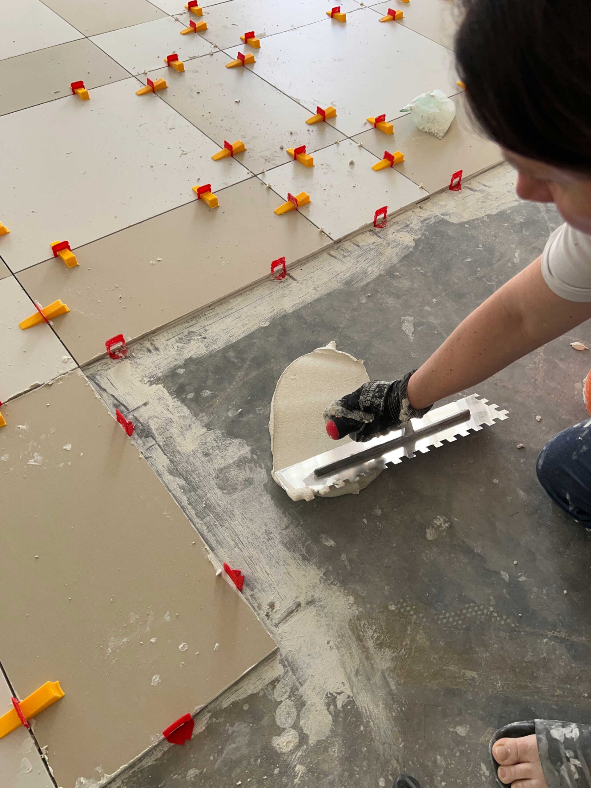 using flat slide of trowel to spread mortar on floor