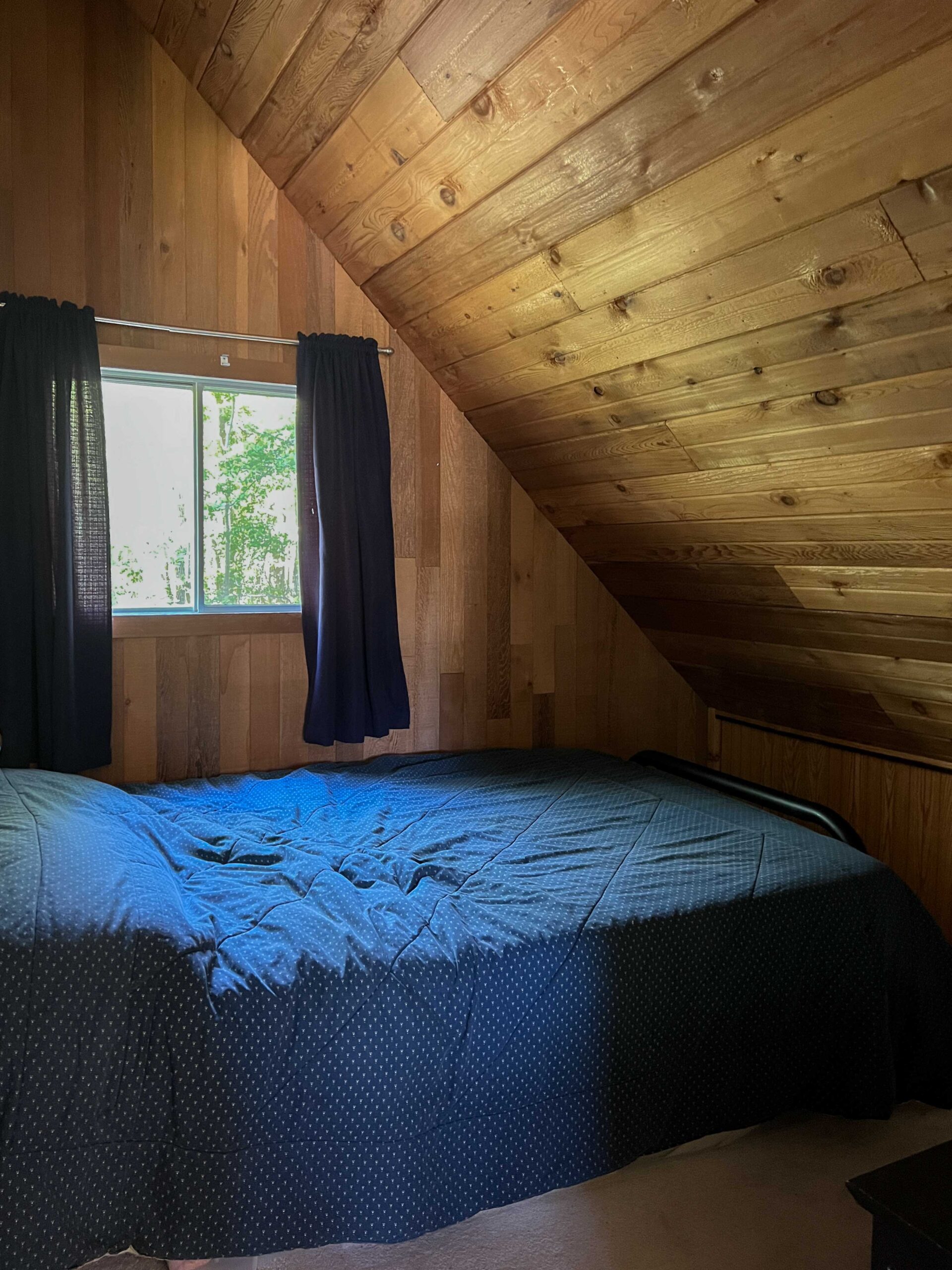 room with angled pine celings and bed and window