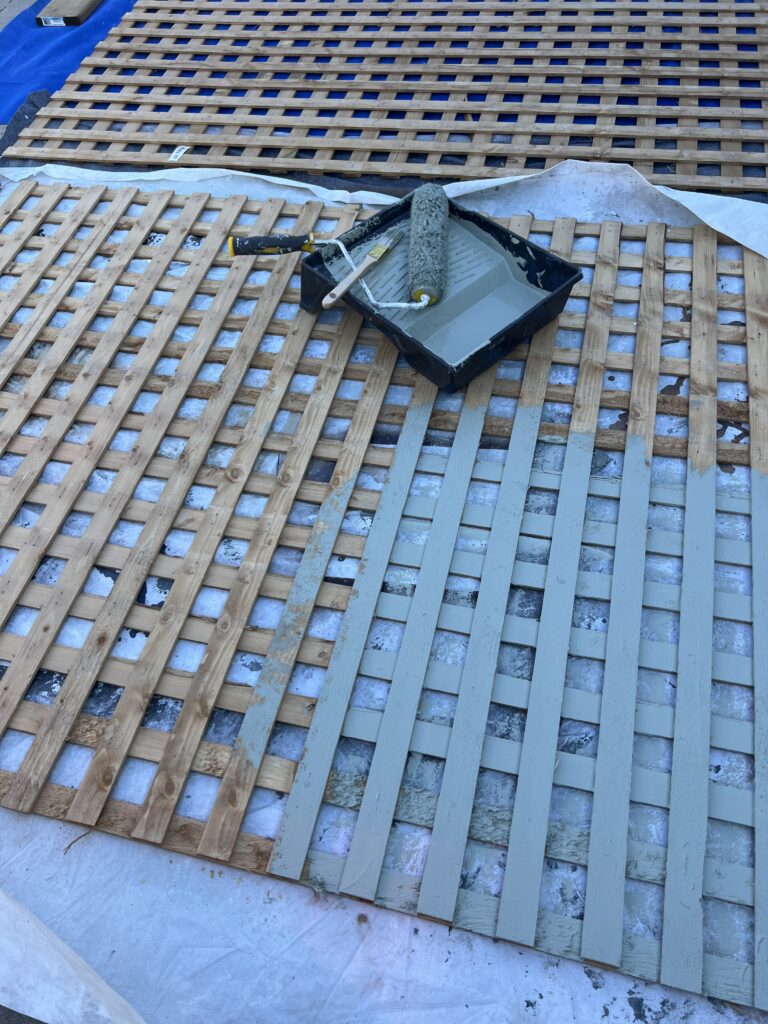 Using a roller to paint the lattice.